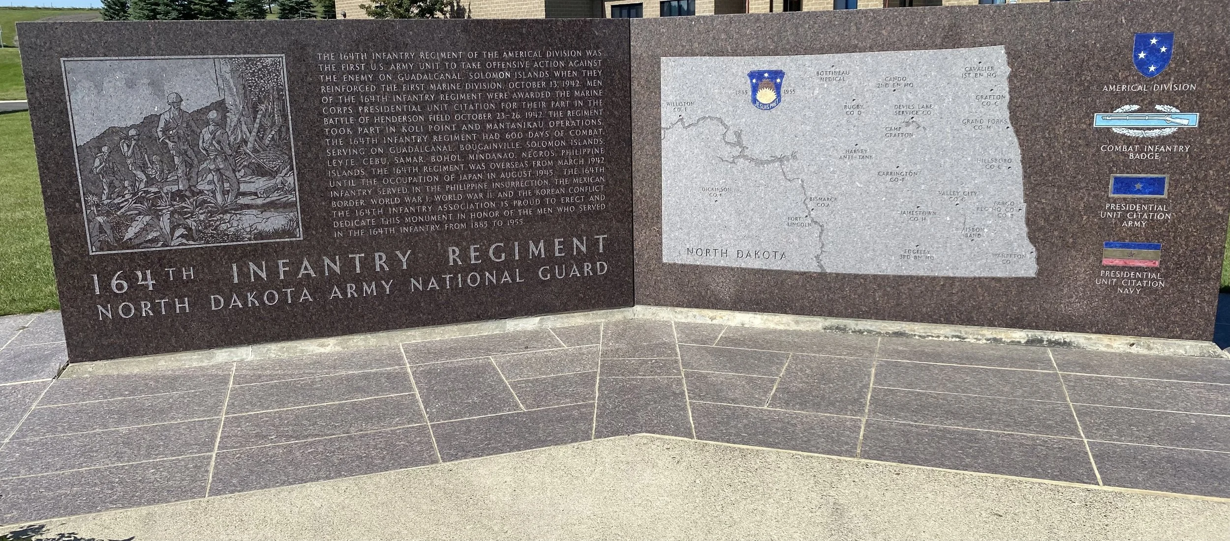 Memorial plaque dedicated to the 164th Infantry Regiment of the North Dakota Army National Guard. It features a historical image of soldiers, a map of North Dakota with locations, and symbols representing military units including the American Division, Combat Infantry Badge, Presidential Unit Citation Army, and Presidential Unit Citation Navy.