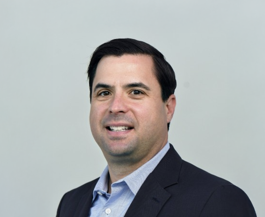 Professional headshot of a man in a business suit against a plain background.
