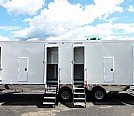 Three white mobile trailers parked side by side under a blue sky with clouds.