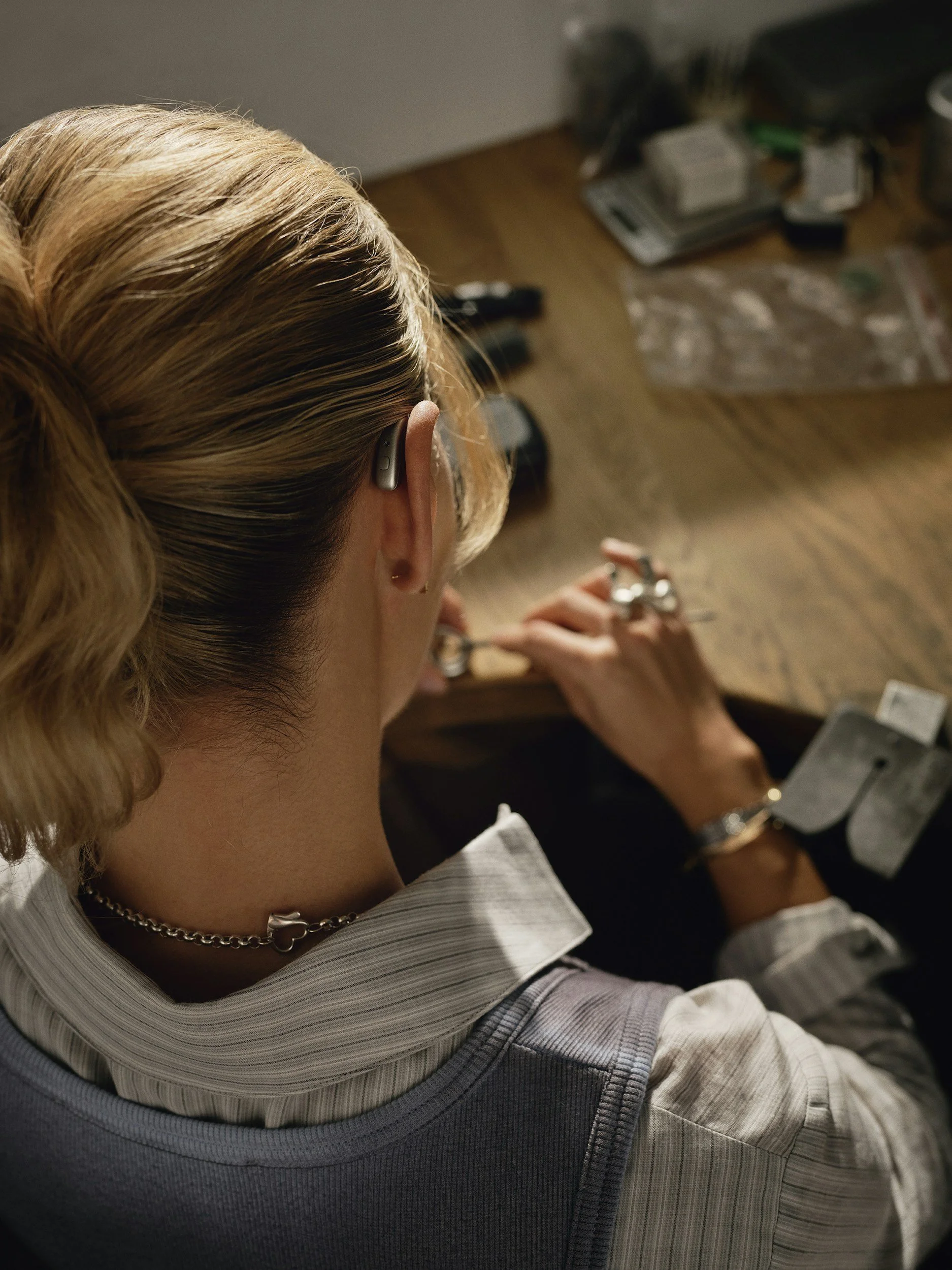 A man operating a green forklift inside a warehouse, moving a white pickup truck with ladders on its roof.