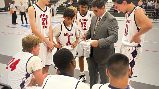 Basketball coach giving instructions to a team of players during a timeout on the court.