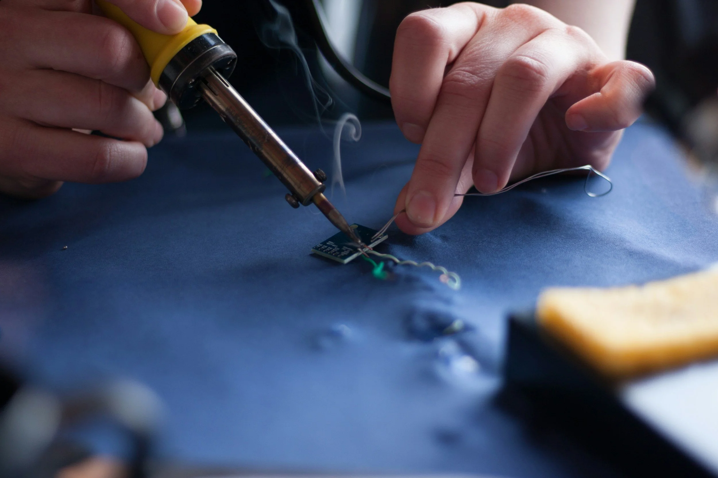 A person soldering electronic components on a circuit board using a soldering iron.