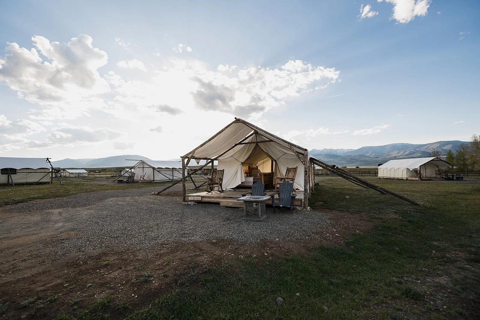 Glamping camp at sunset with tents silhouetted against a colorful sky in Montana