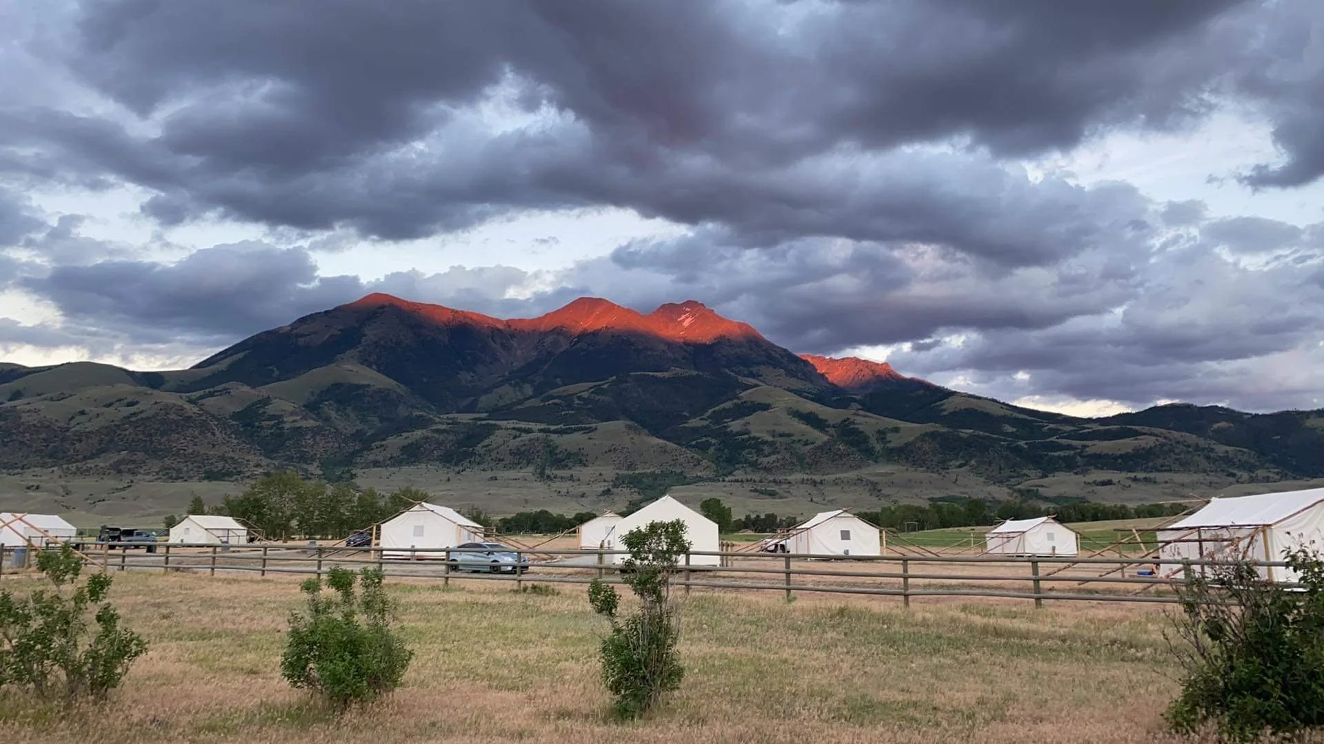 Glamping camp at night with illuminated tents under a dark Montana sky