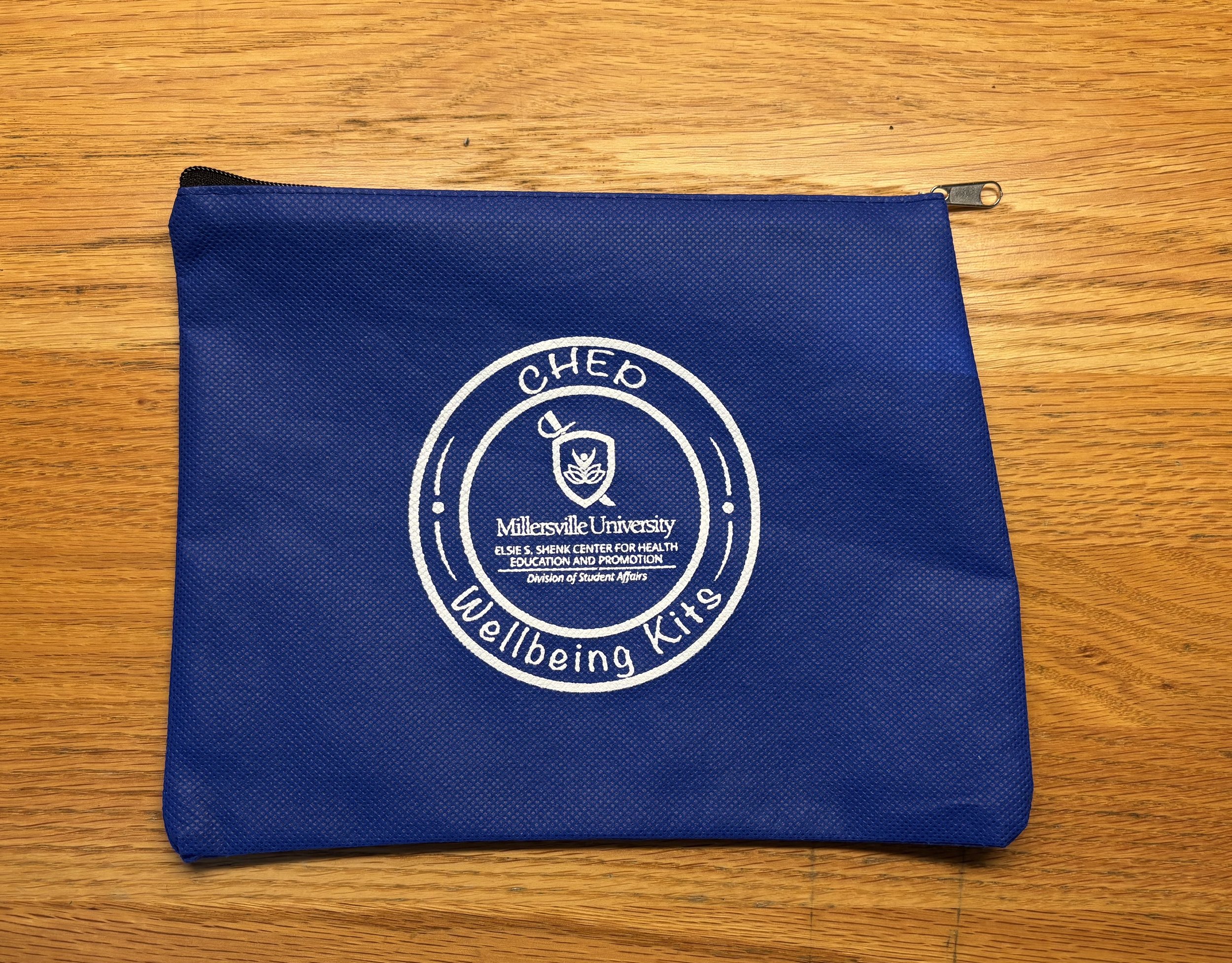 Blue fabric pouch with white logo and text for Millersville University and division of student affairs on a wooden surface.