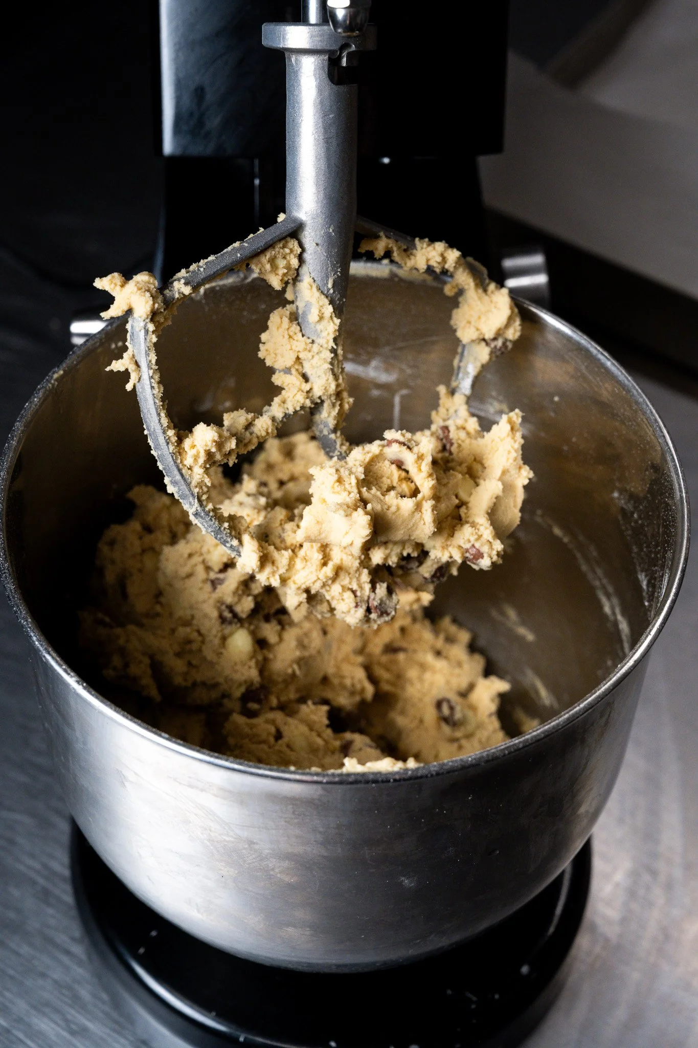 Mixing cookie dough with an electric stand mixer in a stainless steel bowl.