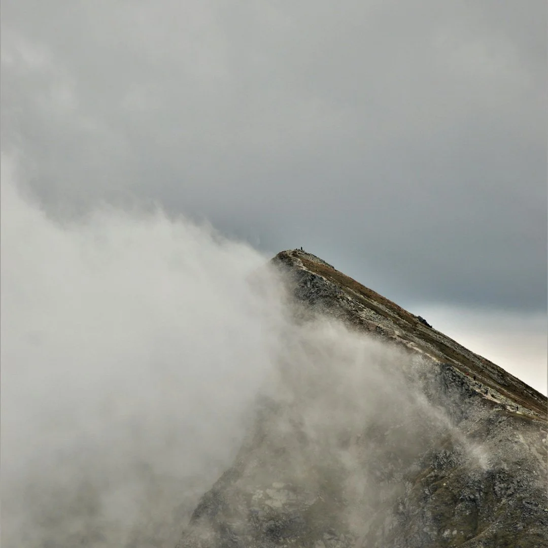 Berggipfel in Nebel gehüllt, Wolken ziehen vorbei, grauer Himmel