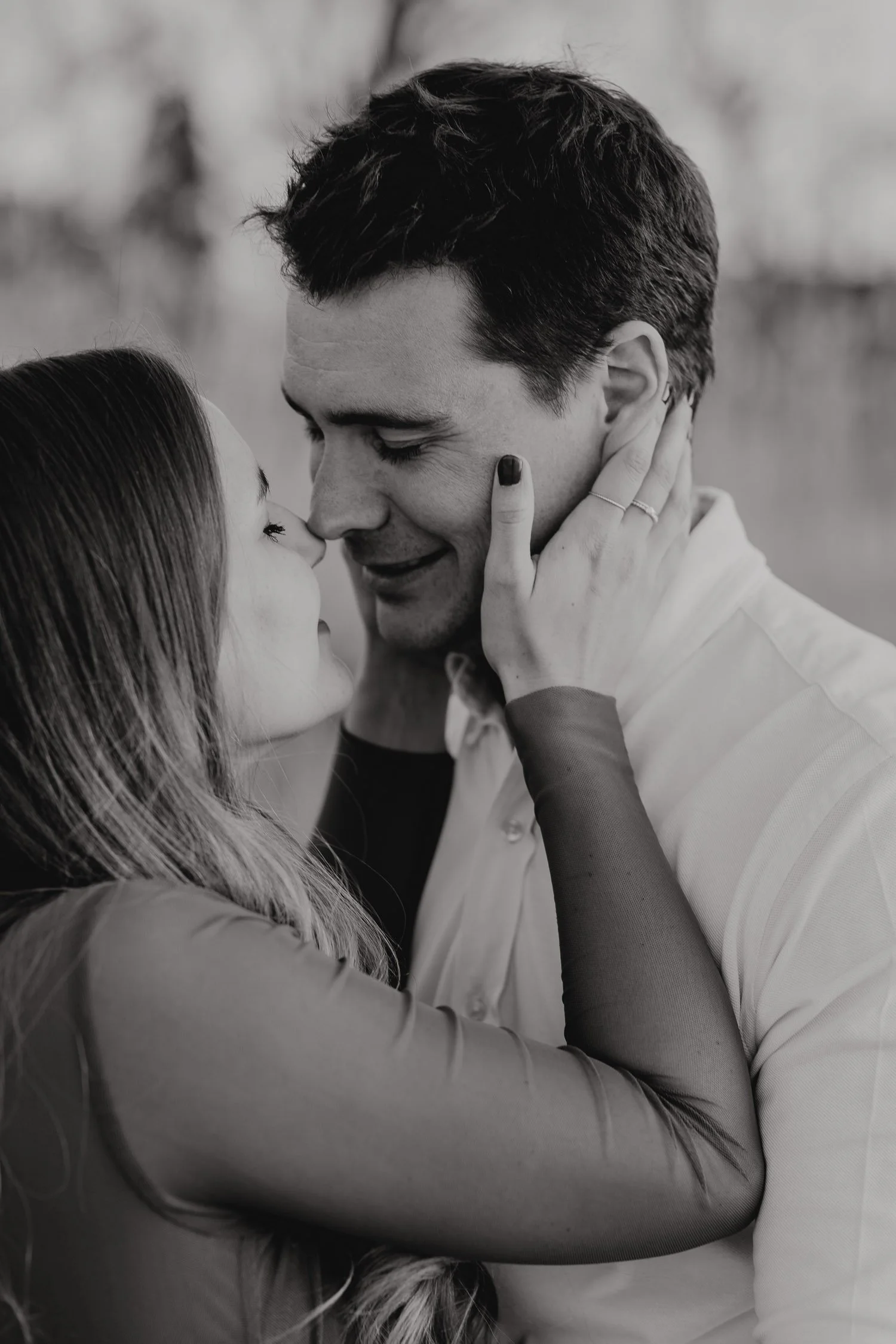 Ein schwarzer und weißer Nahaufnahme-Foto eines liegenden Paares, das sich umarmt und zusammen küsst, mit geschlossenen Augen, in einem emotionalen Moment.