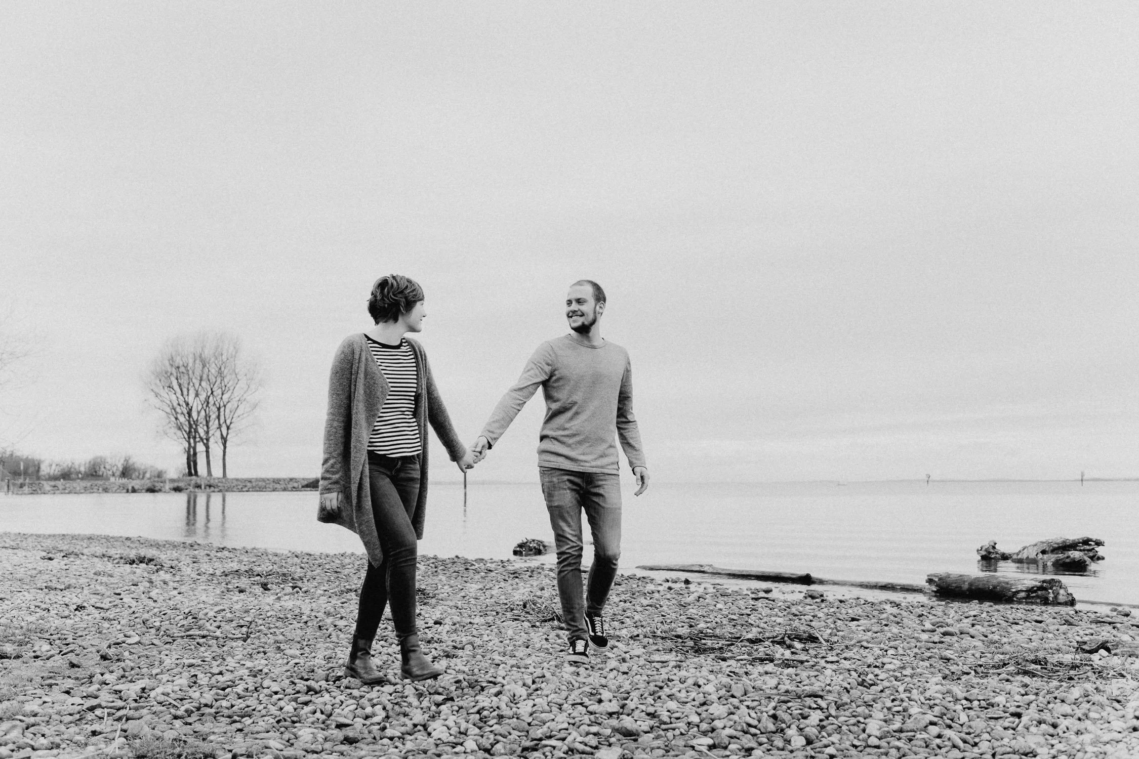 Ein Paar geht Hand in Hand am Strand entlang bei Sonnenuntergang.