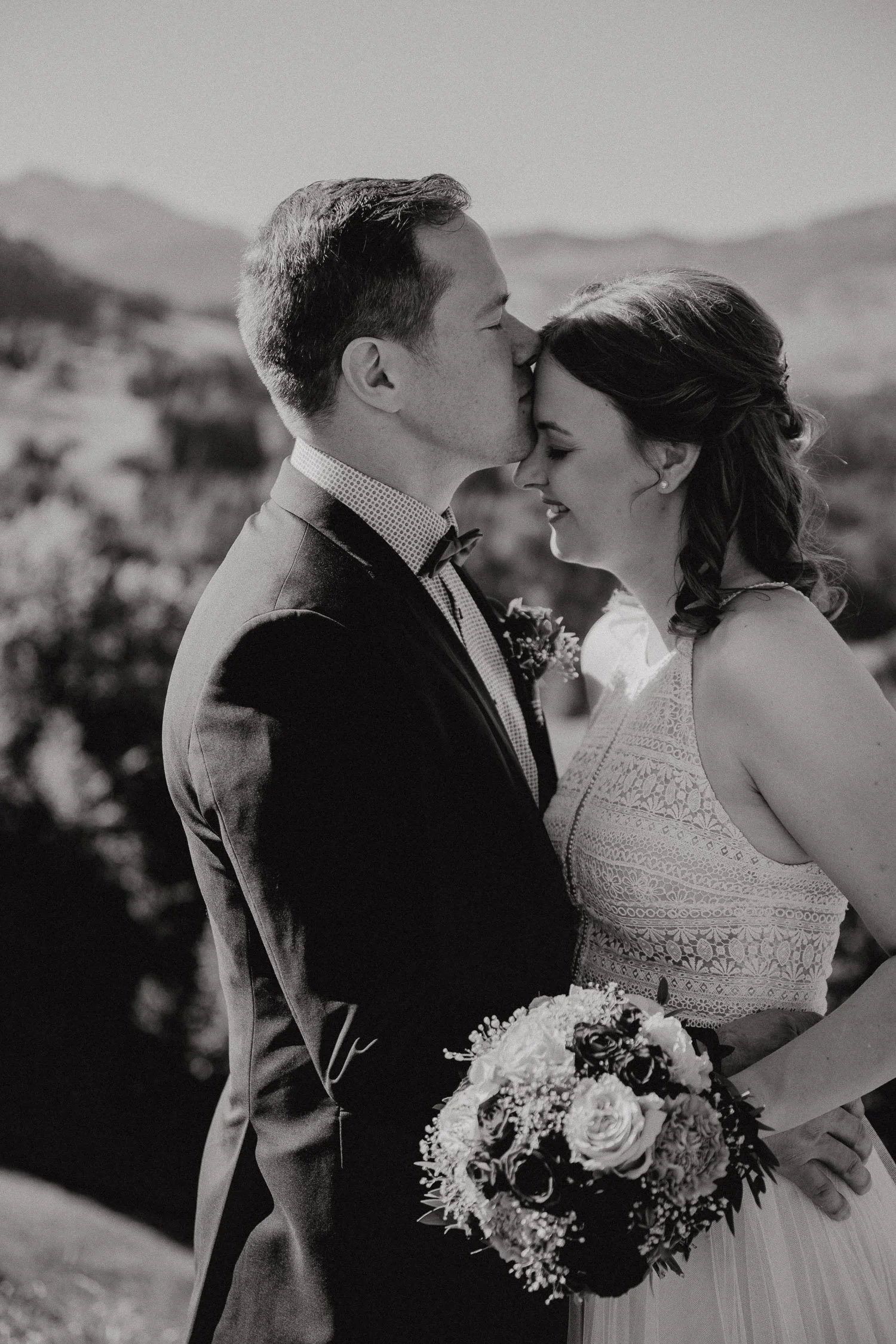 Braut und Bräutigam bei der Hochzeit, vor bergigem Hintergrund, in Schwarz-Weiß.