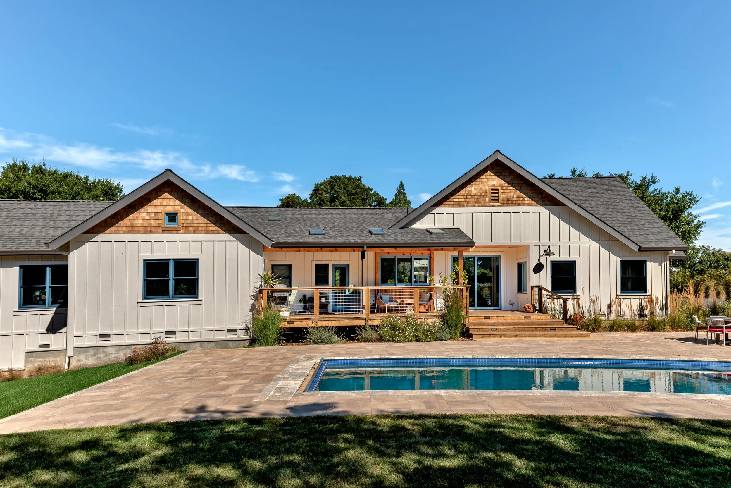 Modern house in Sebastopol with a backyard pool, patio, and deck, surrounded by landscaping and trees under a blue sky.