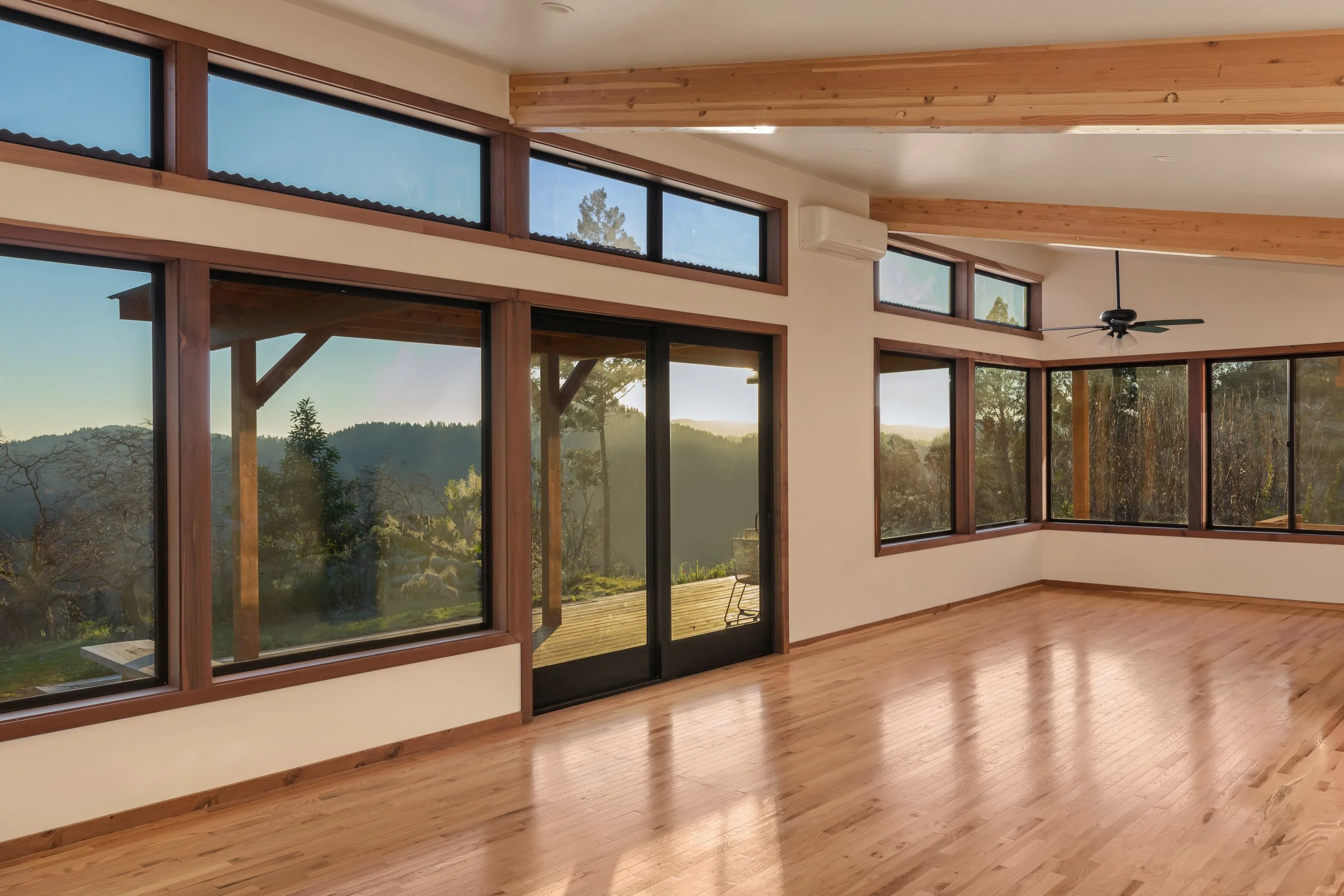 Interior of a room with large windows showing a scenic landscape with hills, trees, and a clear sky.