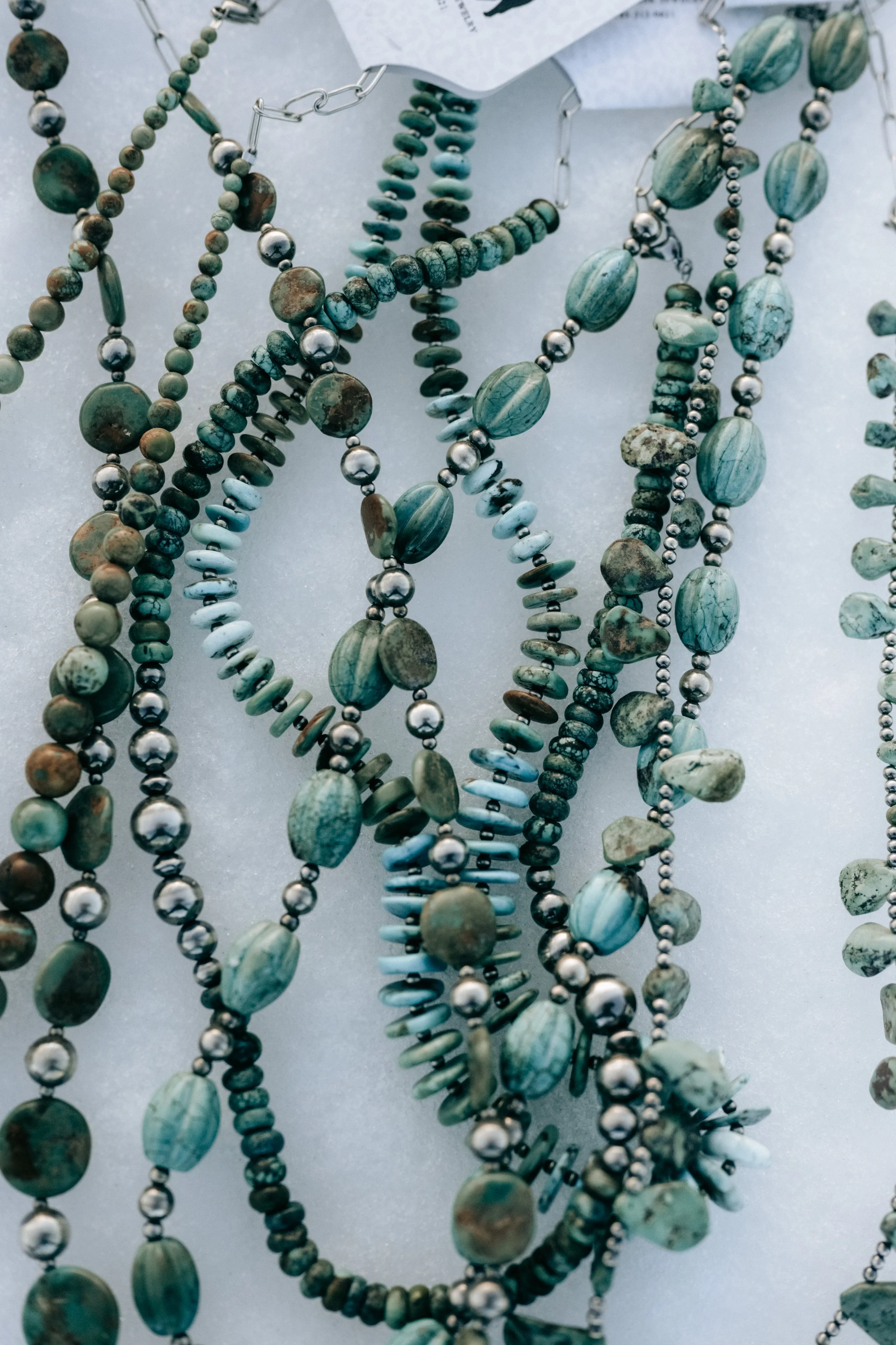 Multiple strands of turquoise and metallic beads laid out on a surface.