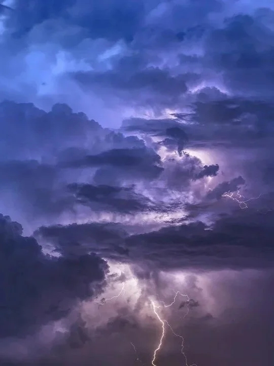 Dark storm clouds with lightning streaks in the sky during a thunderstorm.