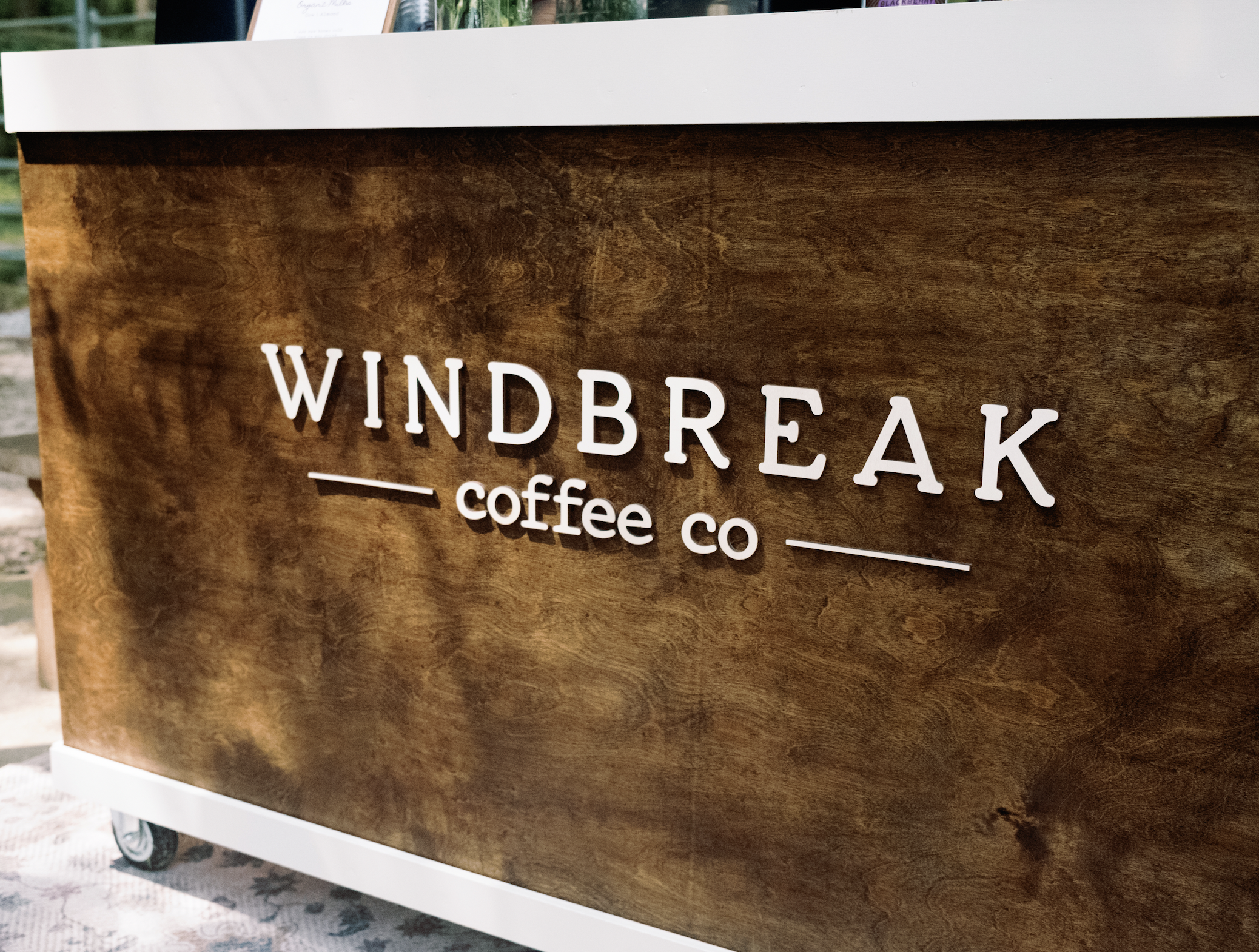 Beautiful coffee cart set up with Windbreak Coffee Co lettering on the front over rich espresso-stained wood