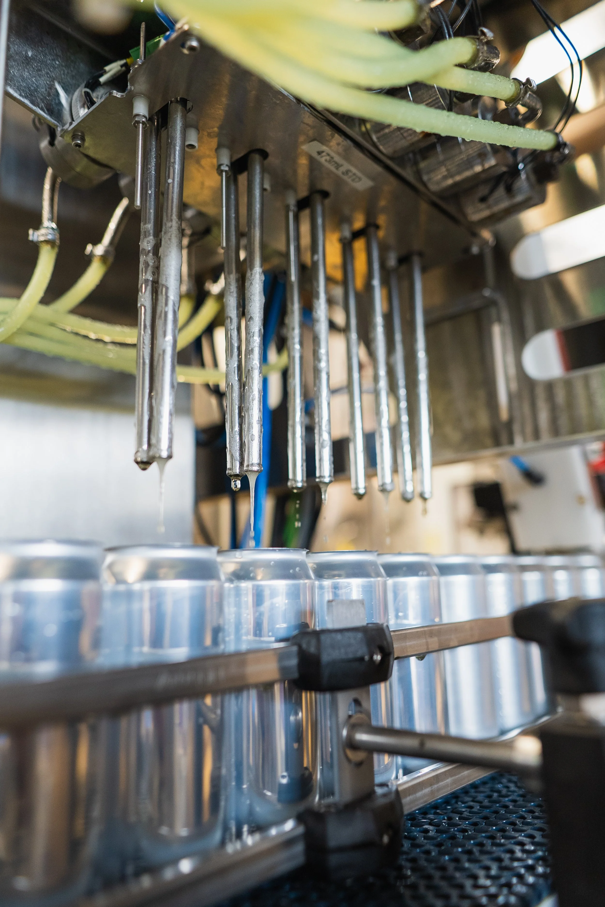 Close-up of an espresso machine creating coffee, with metallic nozzles dripping liquid into aluminum cups.
