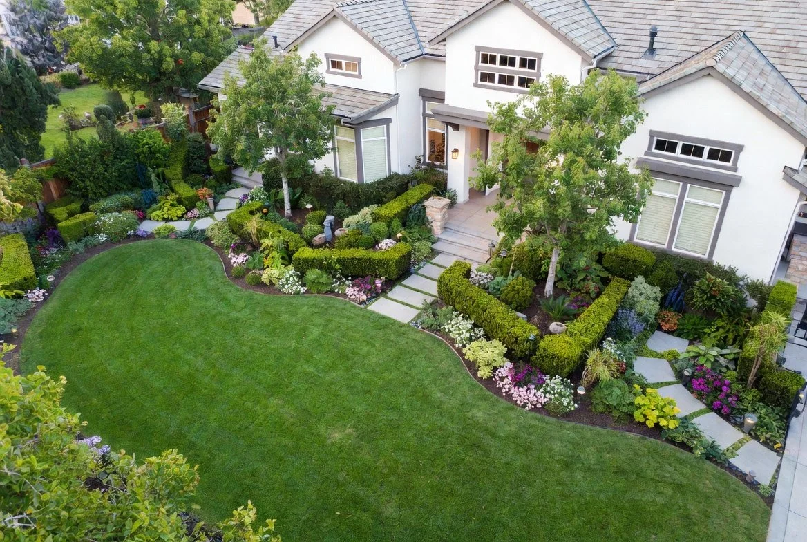 Aerial view of pristine Medford OR landscaping: manicured lawns, curved stone paths, vibrant flower beds, sculpted hedges & trees. Expert construction & design services.