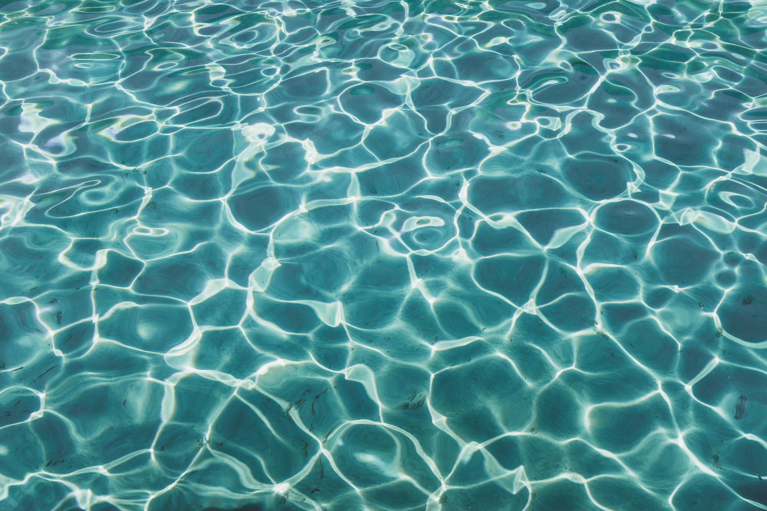 Clear blue water with sunlight reflecting, creating a pattern of ripples and lines.