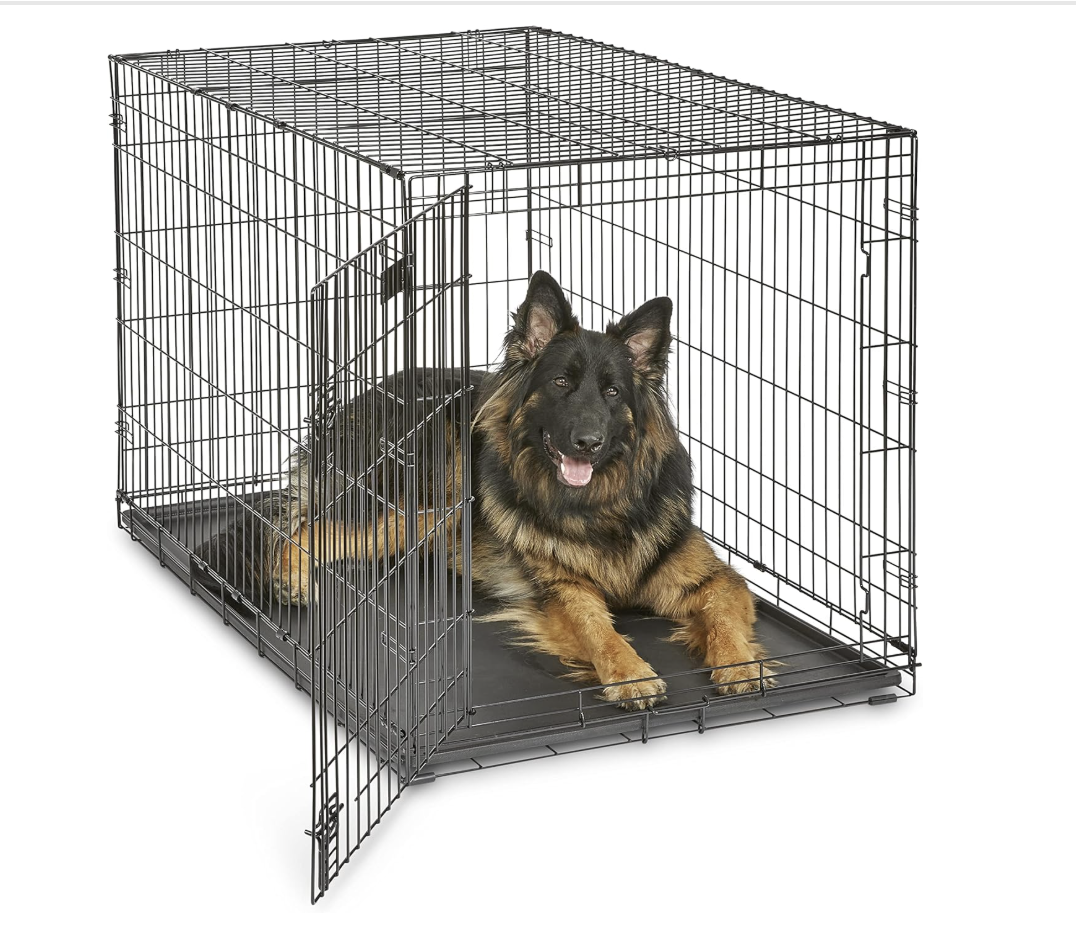 A German Shepherd dog lying inside a metal wire crate with one door open.
