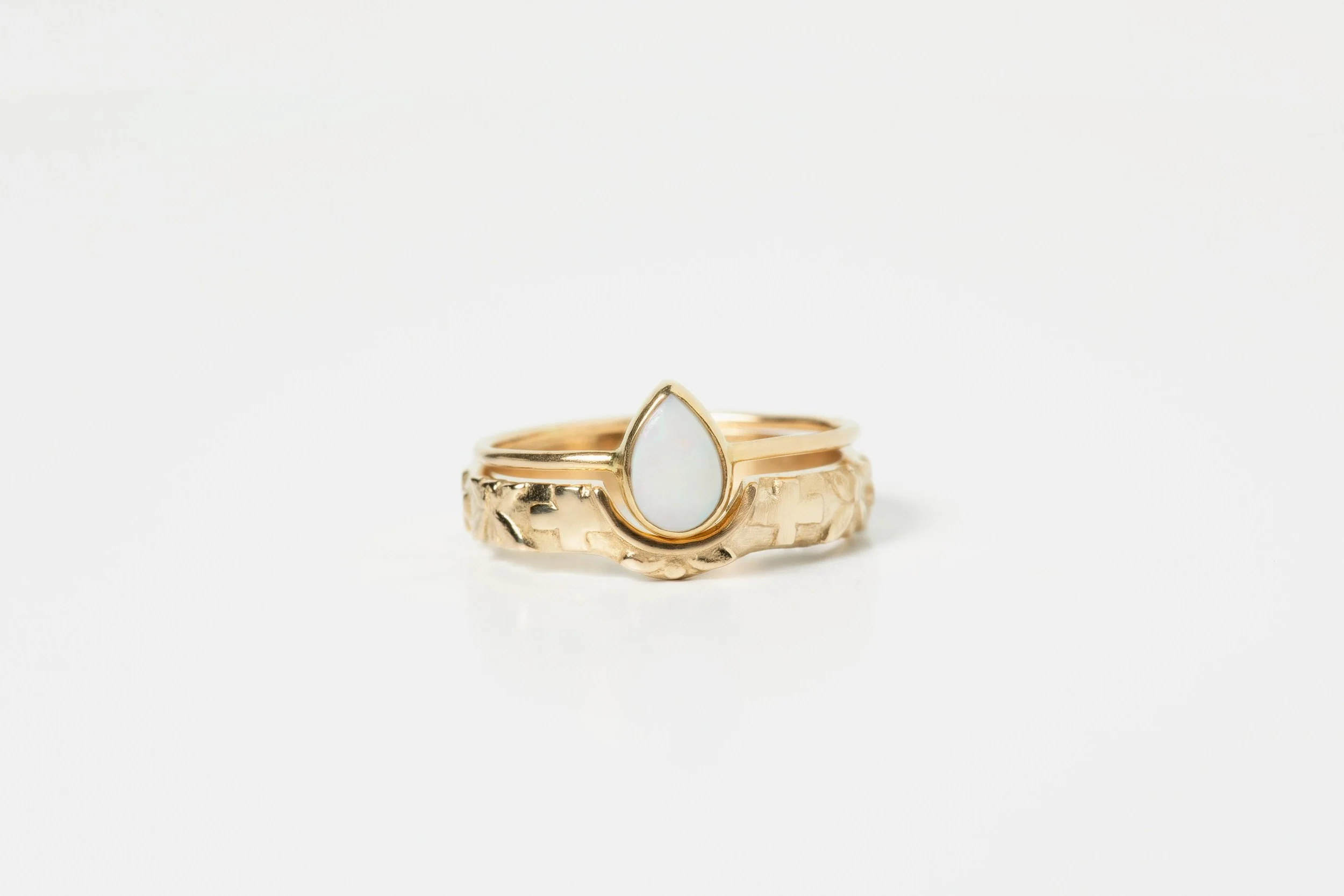 Gold ring with a teardrop-shaped opal gemstone on a plain white background.