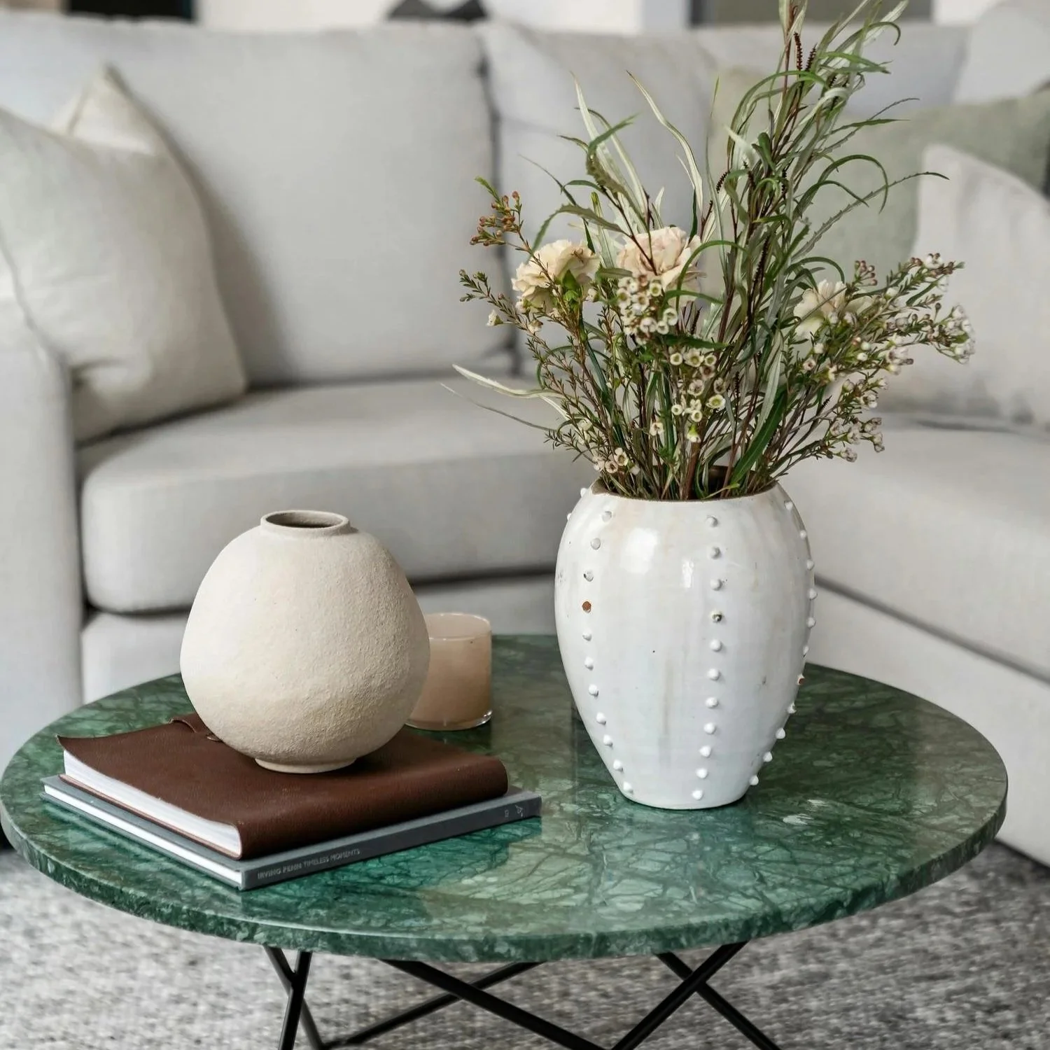 green marble coffee table with floral vase and books