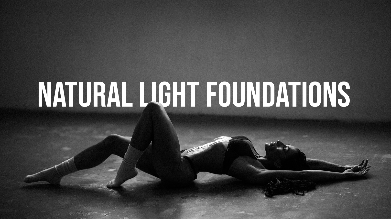 A woman lying on her back on the floor with one leg bent and the other extended, wearing socks and underwear, with the text "Natural Light Foundations" overlaid.