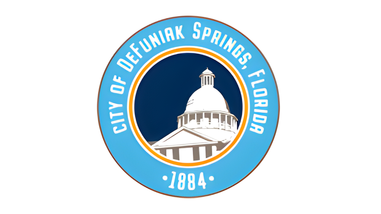 Seal of the City of DeFuniak Springs, Florida, showing a white domed building on a dark blue background, encircled by a light blue band with white text and the year 1884.