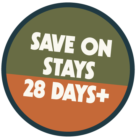 A circular promotional badge with green and orange sections, displaying the text "SAVE ON STAYS 28 DAYS+" in bold white font.