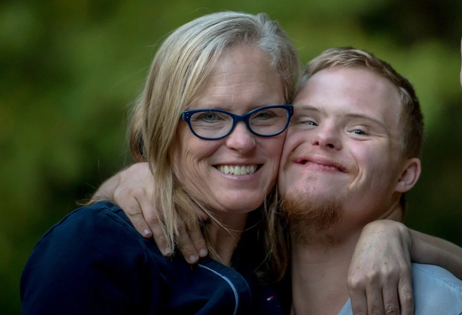 And women happily imbracing a teenage boy with Down Syndrome.