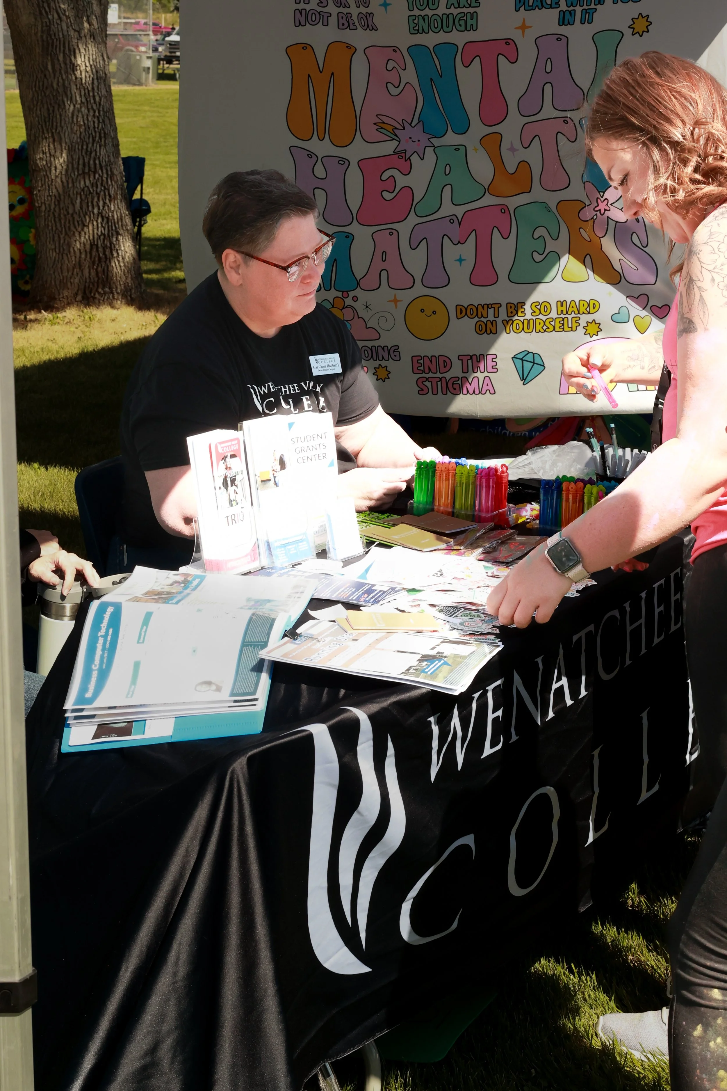 Photo of a Wenatchee Valley College vendor talking to a community member at OBHC's 2026 Color Walk.