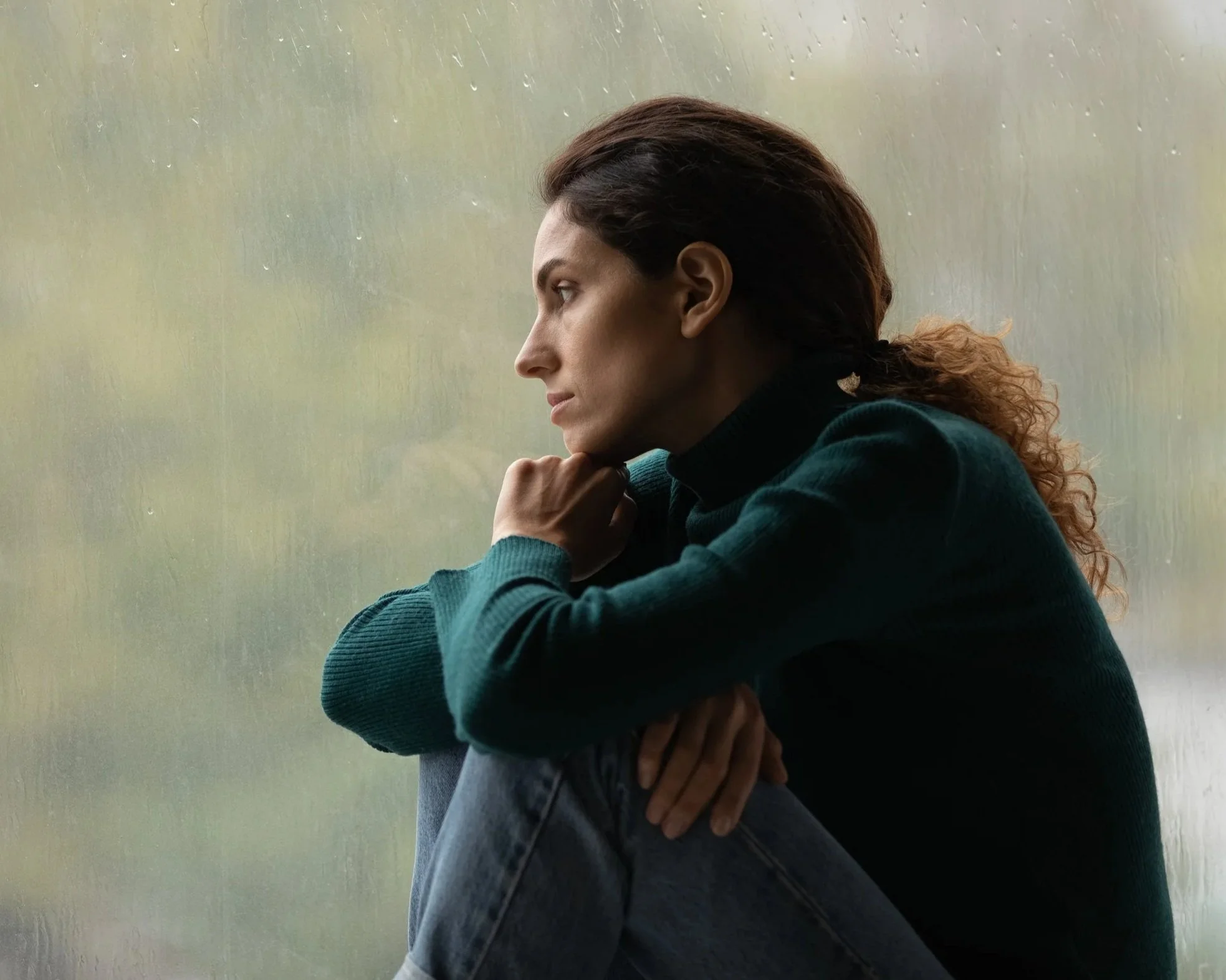 A woman struggling emotionally, looking out the window.