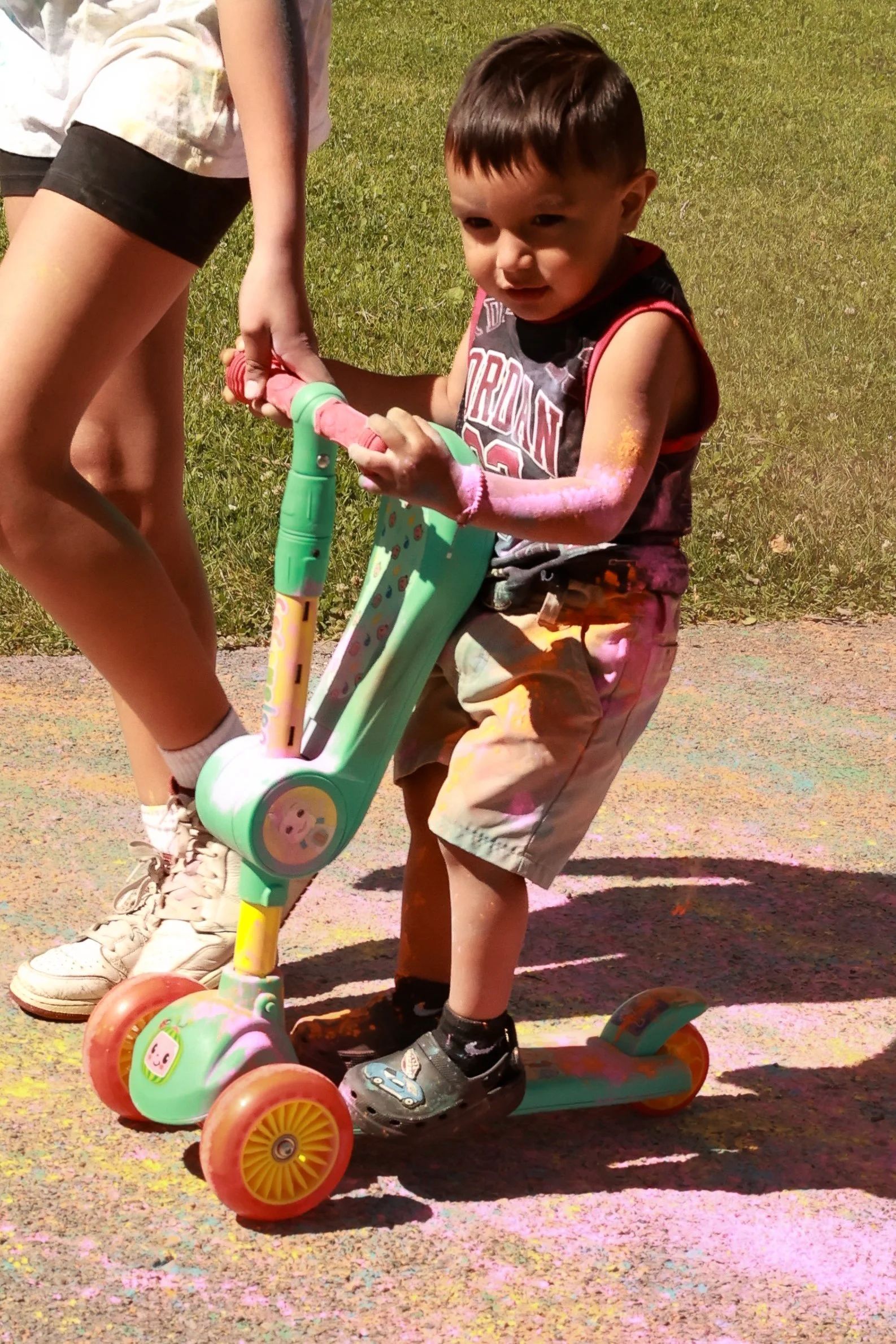 Photo of a young boy being pulled on his scooter at OBHC's 2026 Color Walk.
