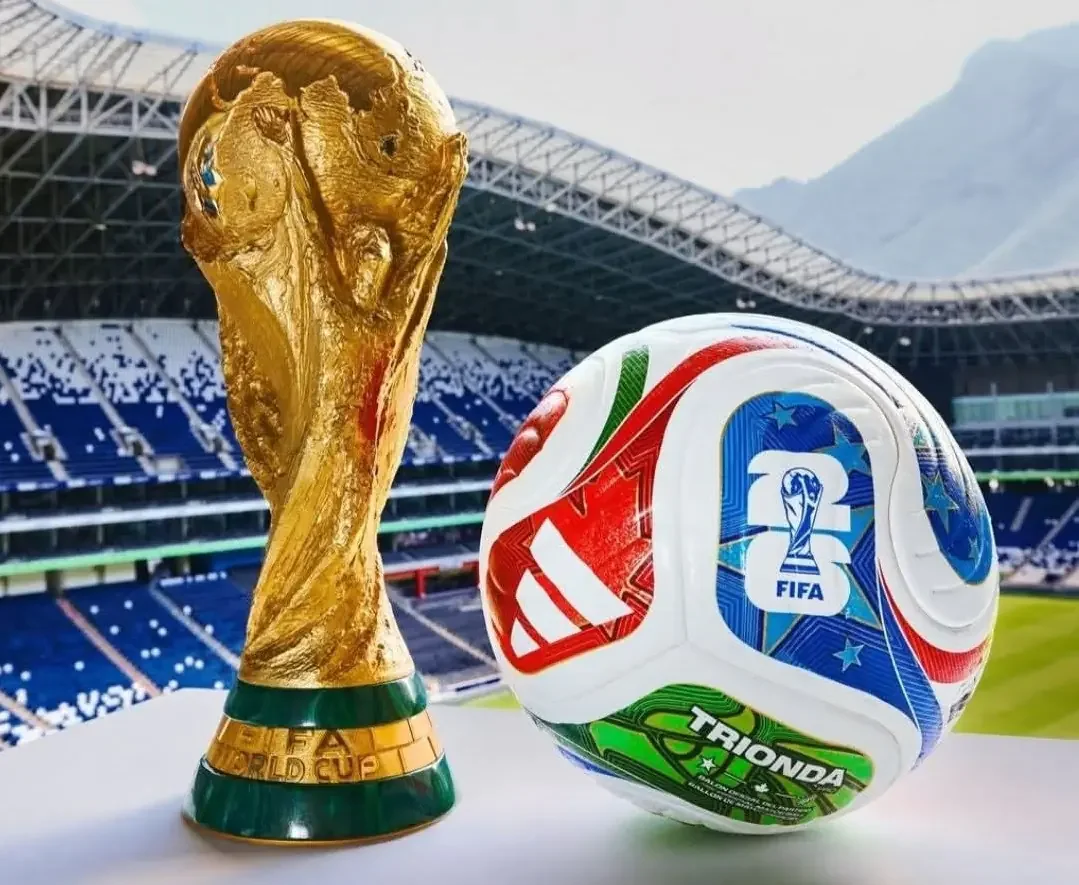 Balón de fútbol de la Copa del Mundo y una réplica del trofeo de la Copa Mundial, en un estadio de fútbol.