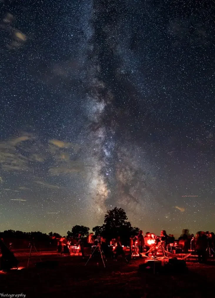 Personas observando el cielo estrellado y la Vía Láctea en una noche despejada.