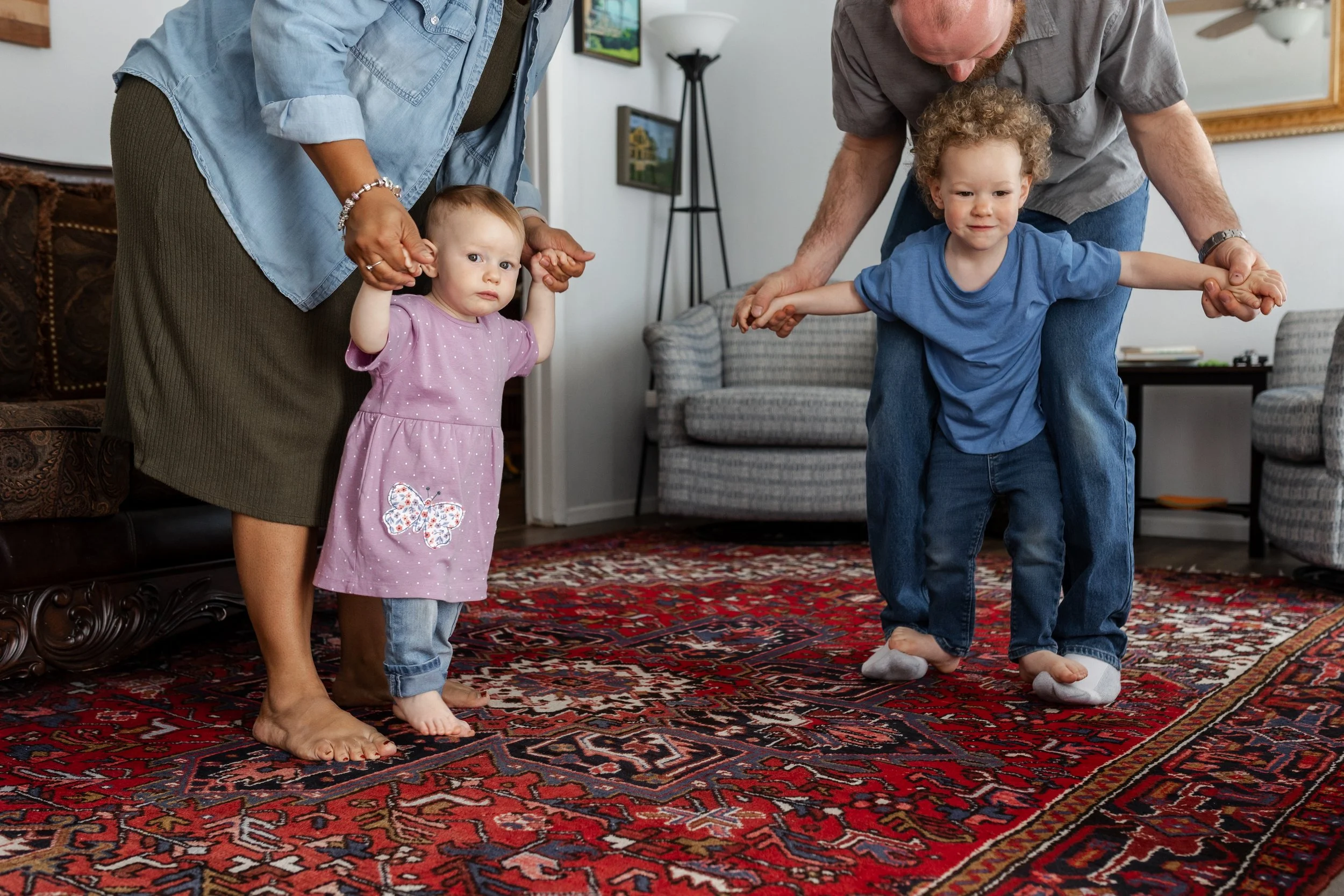young children dancing on parents feet in living room located in Colorado Springs