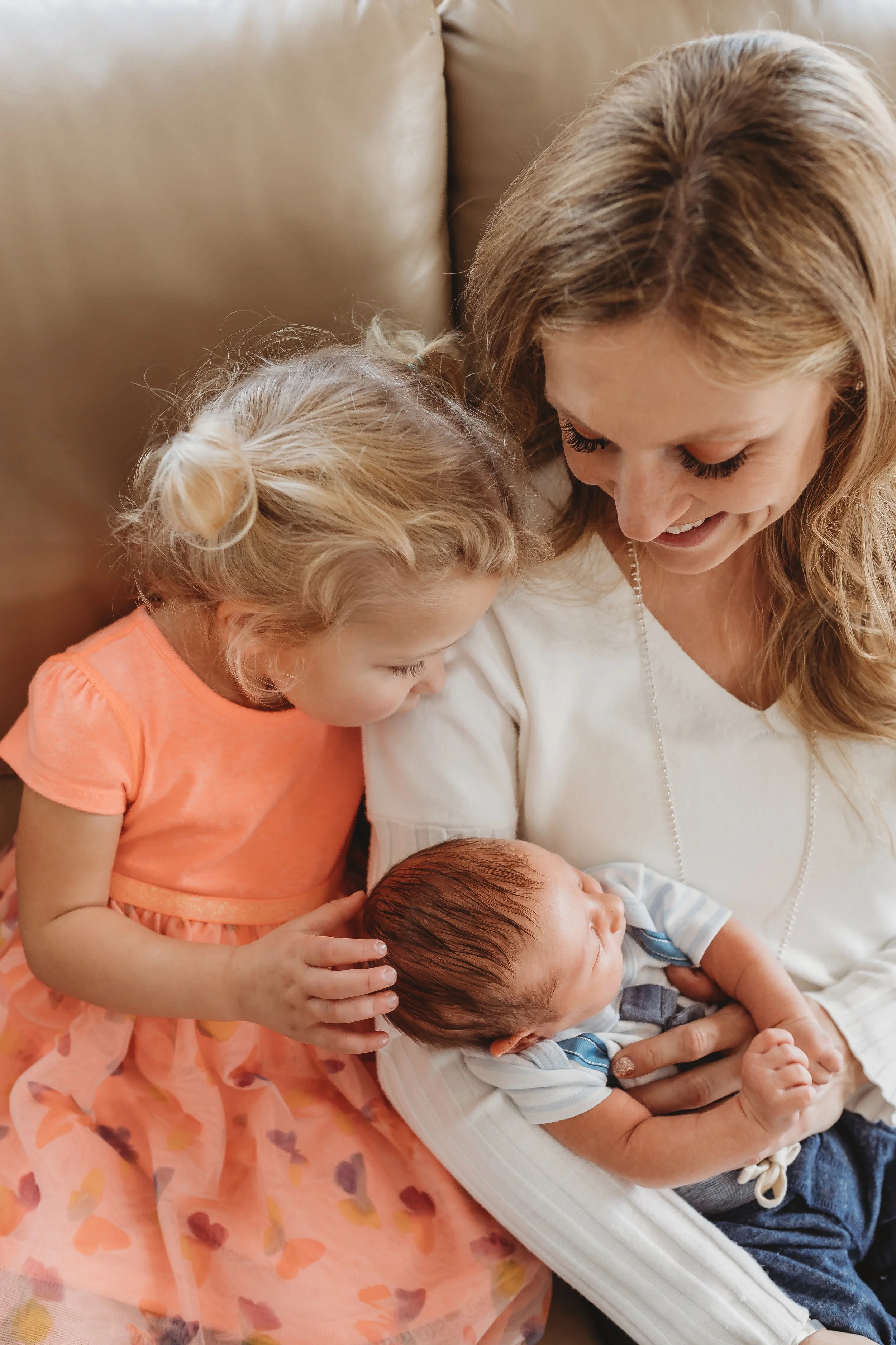 Mom-and-daughter-snuggling-newborn-on-couch-colorado-springs.jpg
