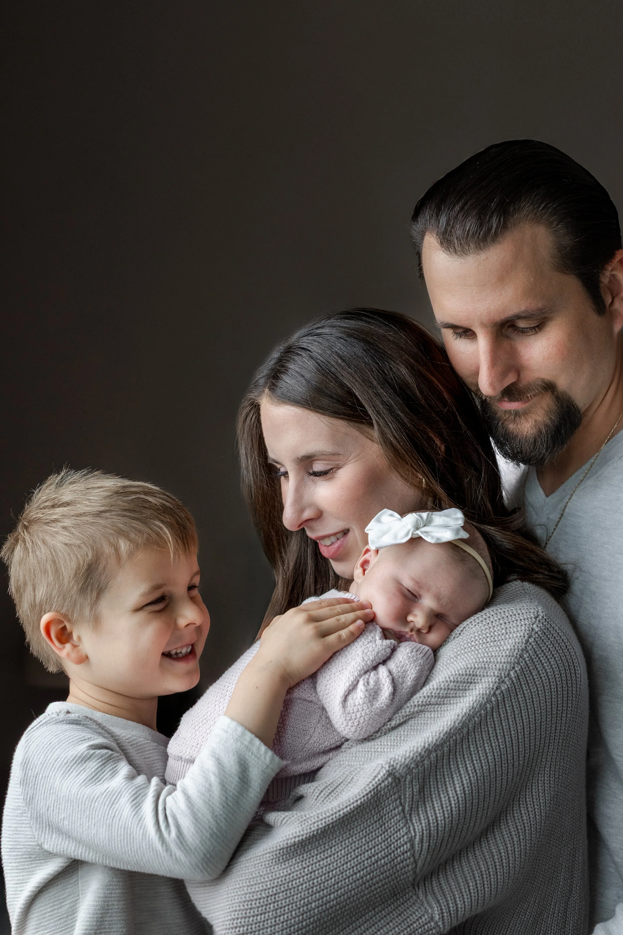 family-of-four-toddler-newborn-window-light-snuggling-close-colorado-springs.jpg
