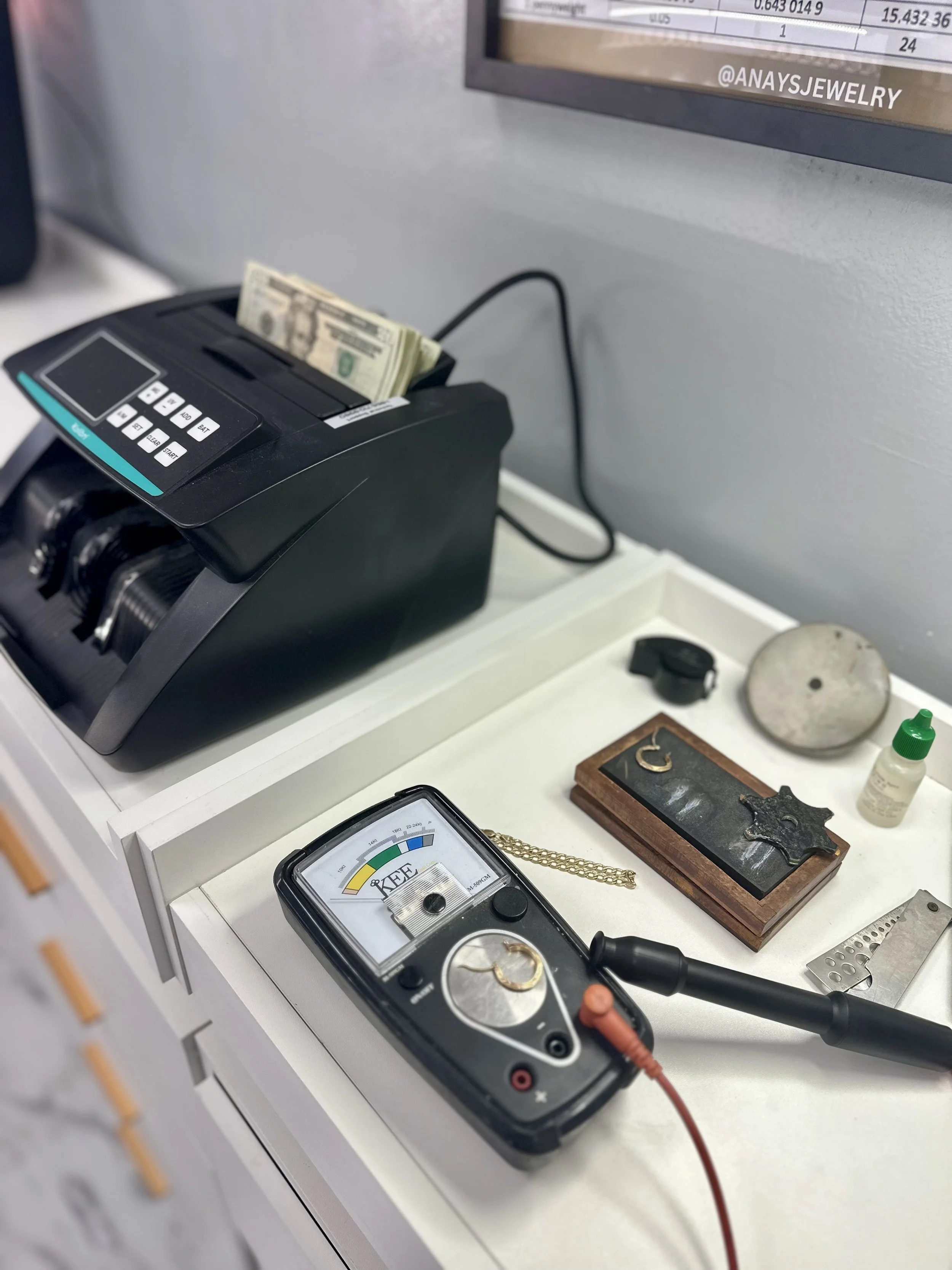 countertop with various gold testing items and cash counter with biills