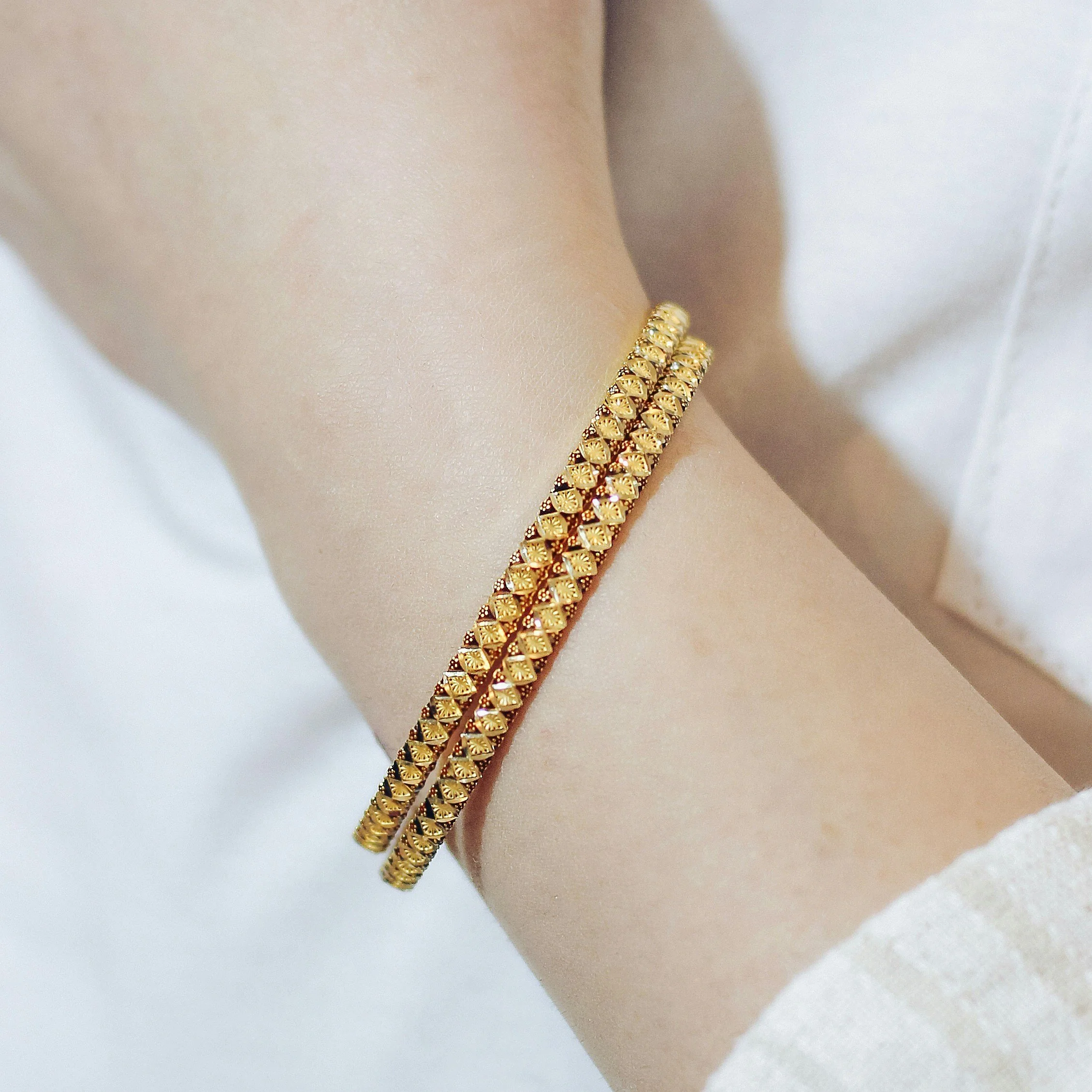 zoom of woman wearing two gold bangles