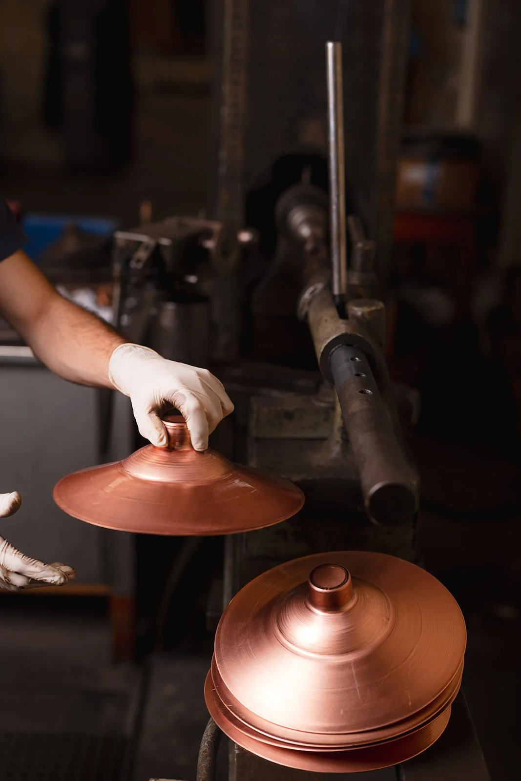 A person wearing gloves polishing a copper plate in a workshop.