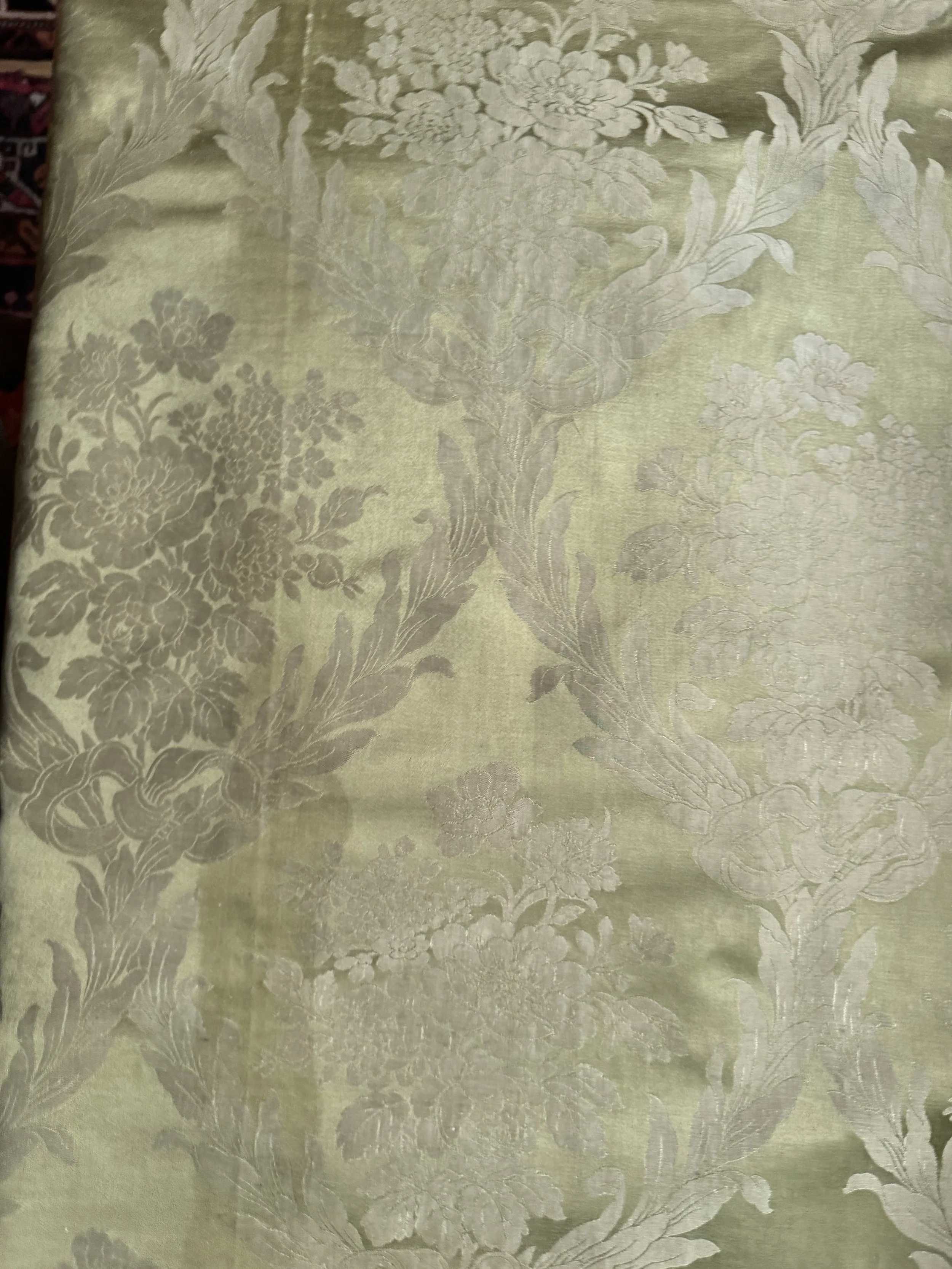 Close-up of a patterned fabric with floral and leaf designs in shades of beige and cream.