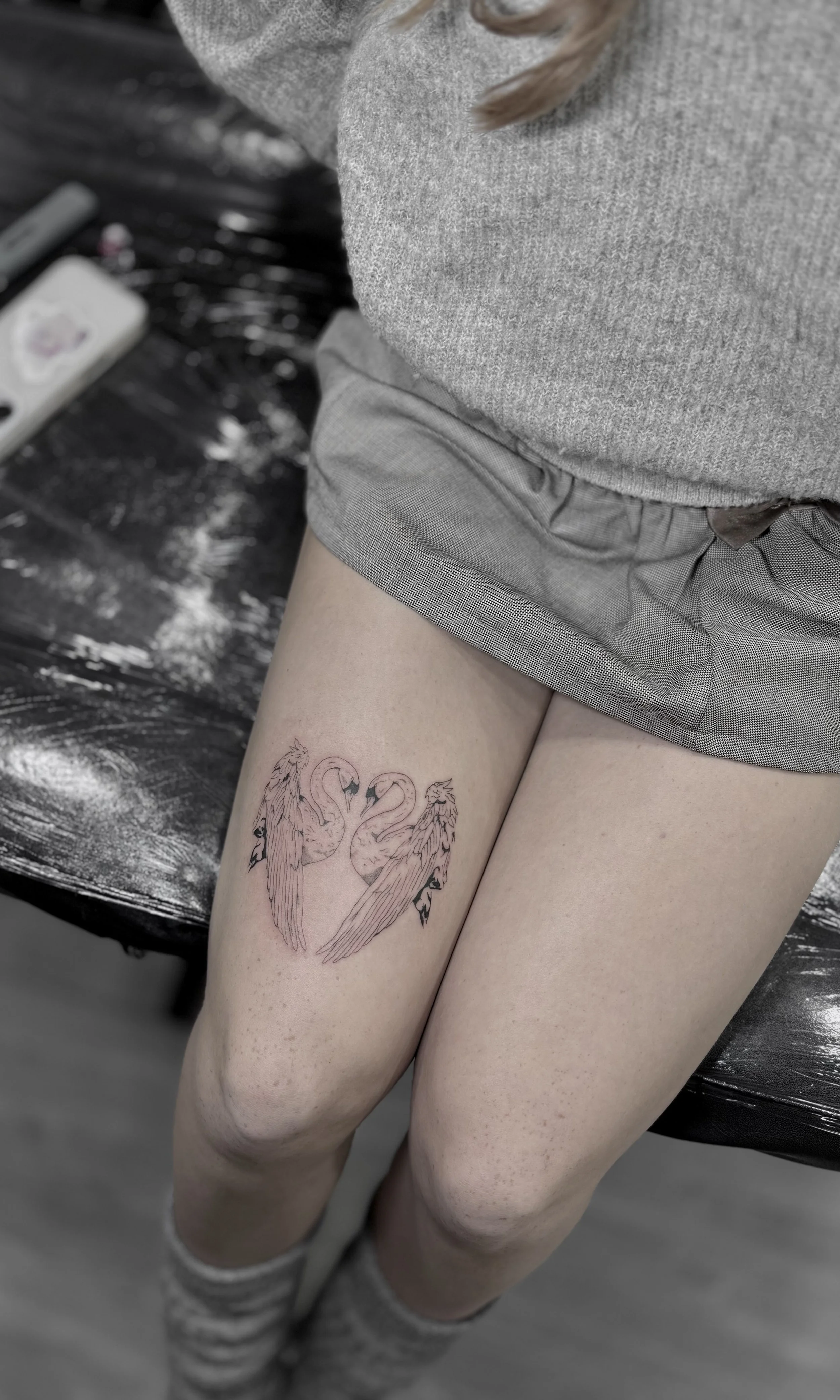 A person with a tattoo of two flamingos facing each other on their upper thigh.