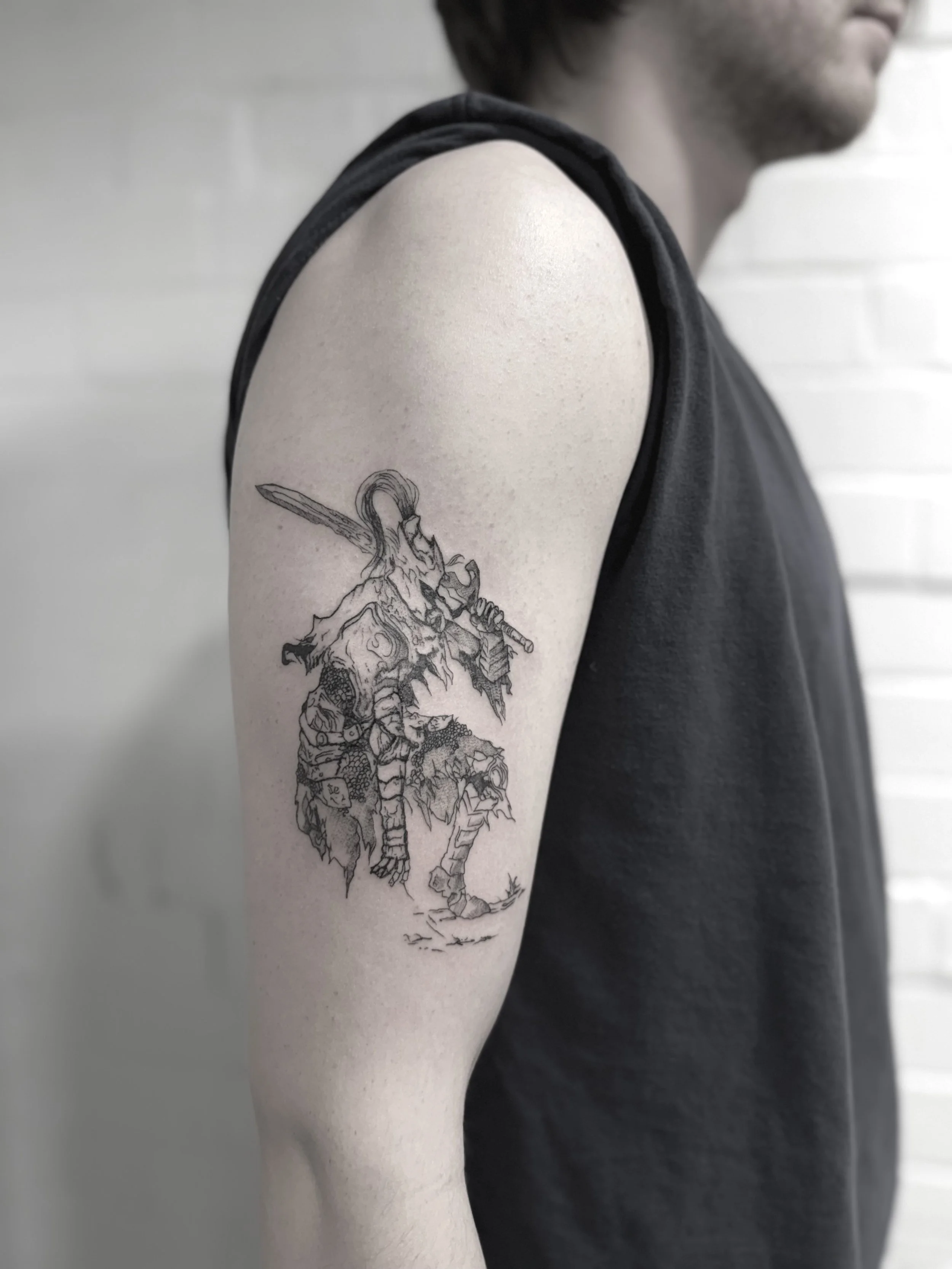 Tattoo of a mythical creature with a sword on person's upper arm.