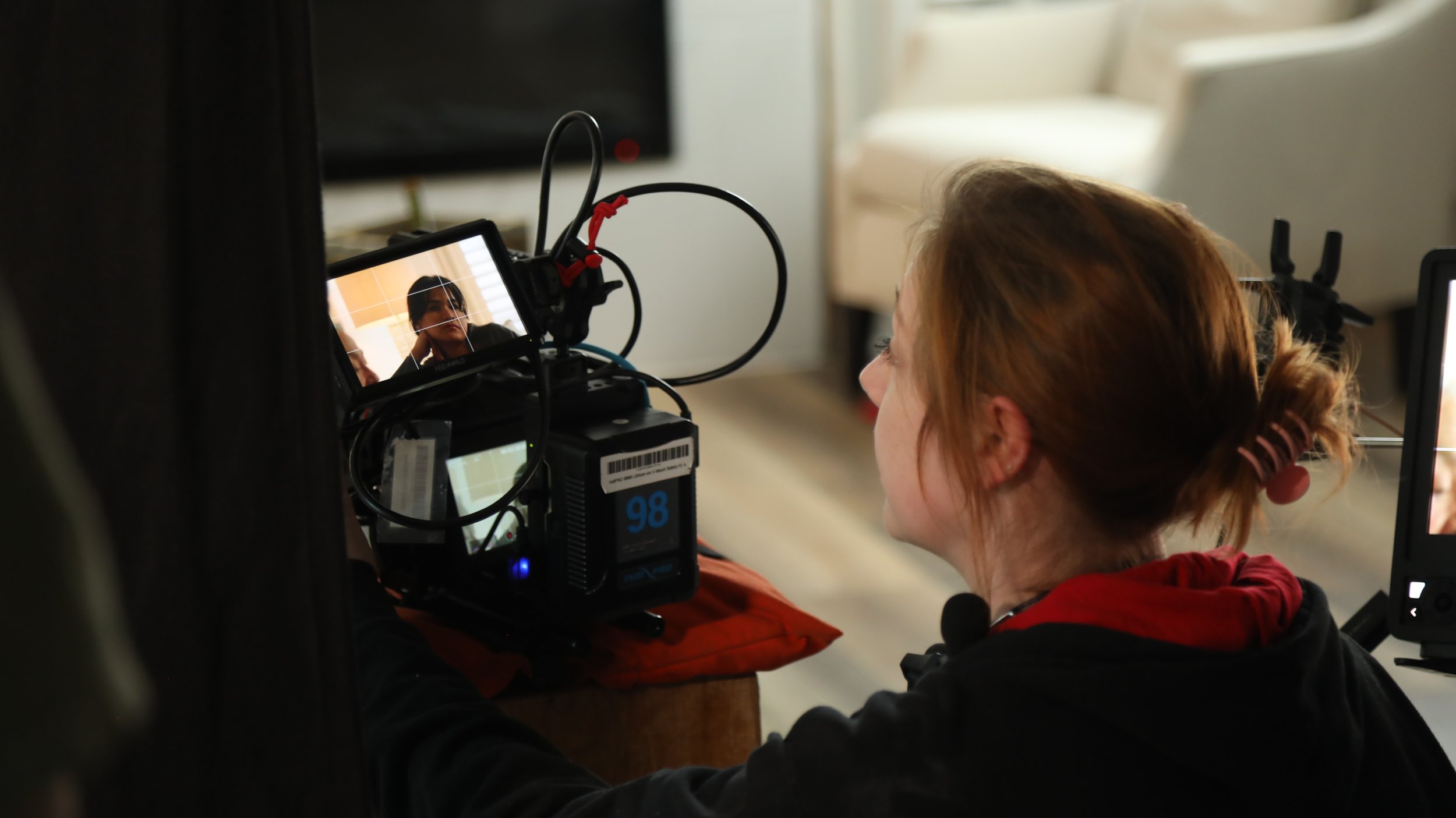 A woman is filming a seated woman with a professional camera, which is focused on her face.