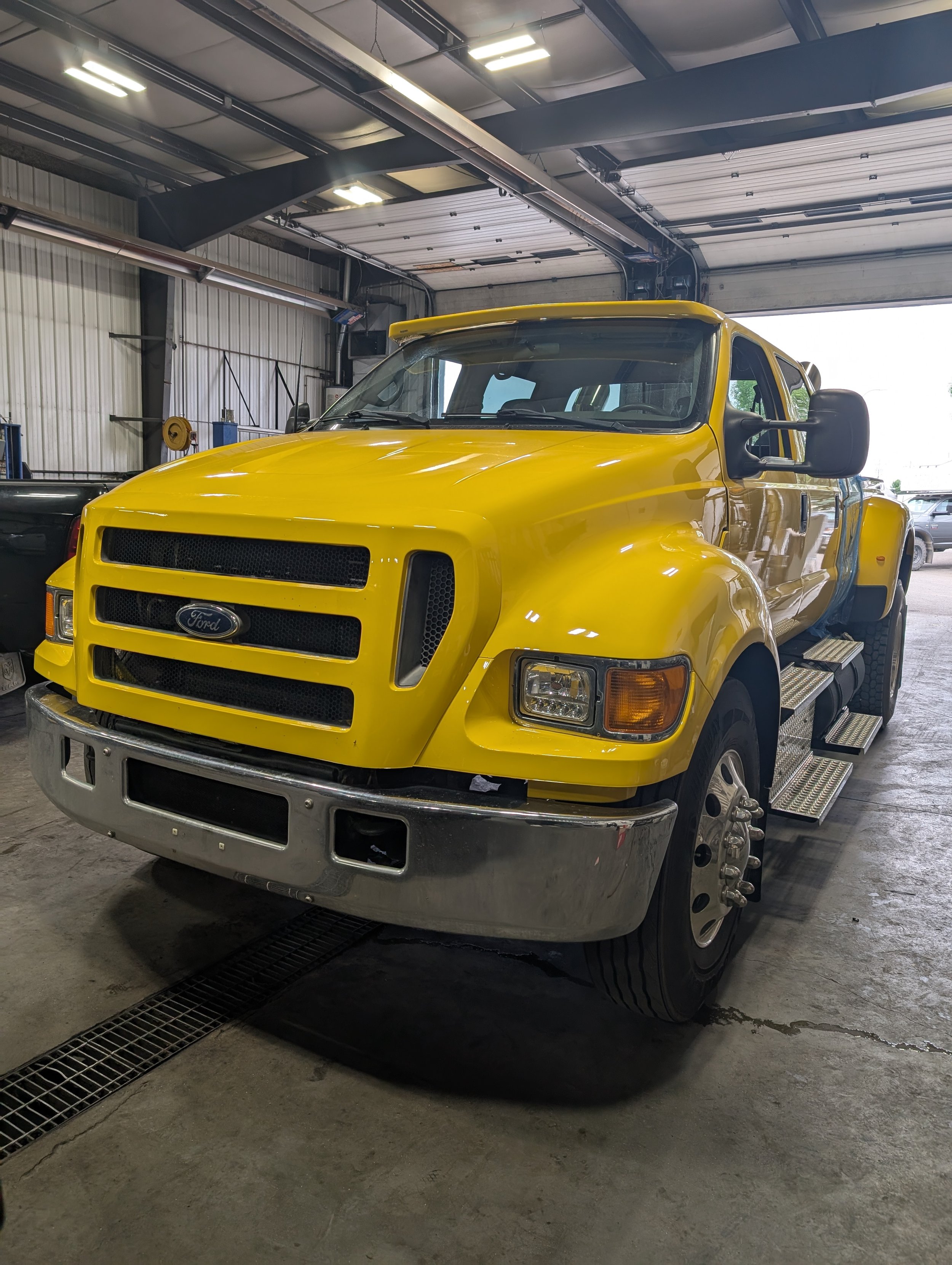 A yellow Ford emergency or utility truck parked inside a garage or warehouse.