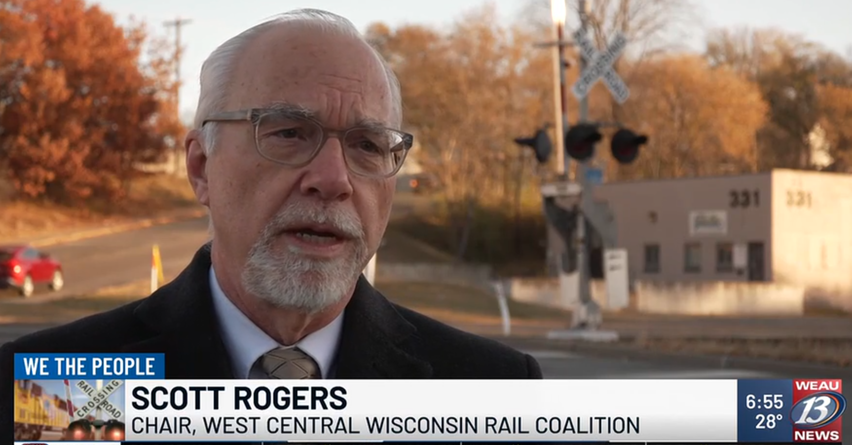 Scott featured on a news segment about the West Central Wisconsin Rail Coalition. He is standing in front of a railroad crossing in Eau Claire.