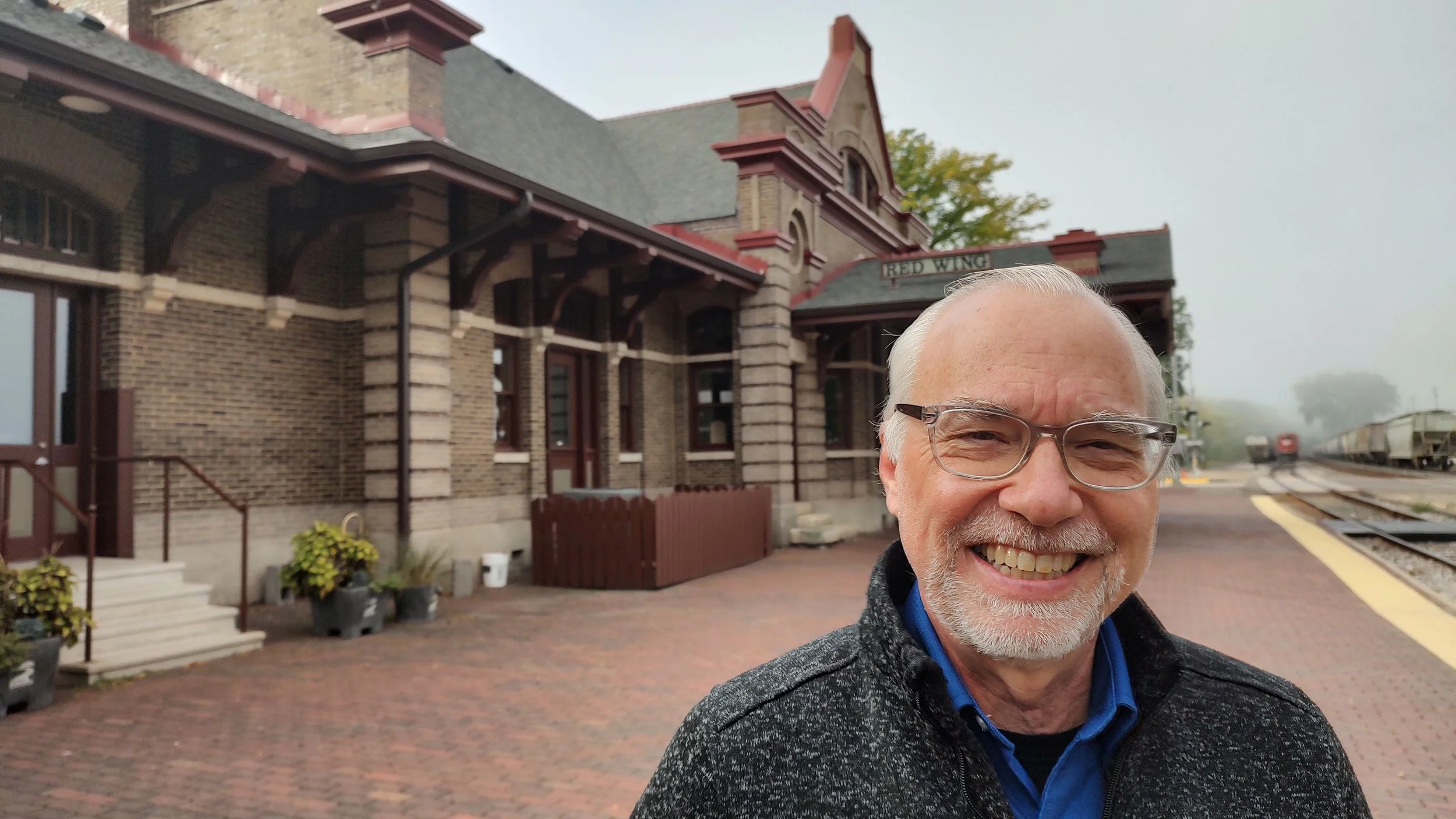 Scott smiling at the camera with a train station in the background.