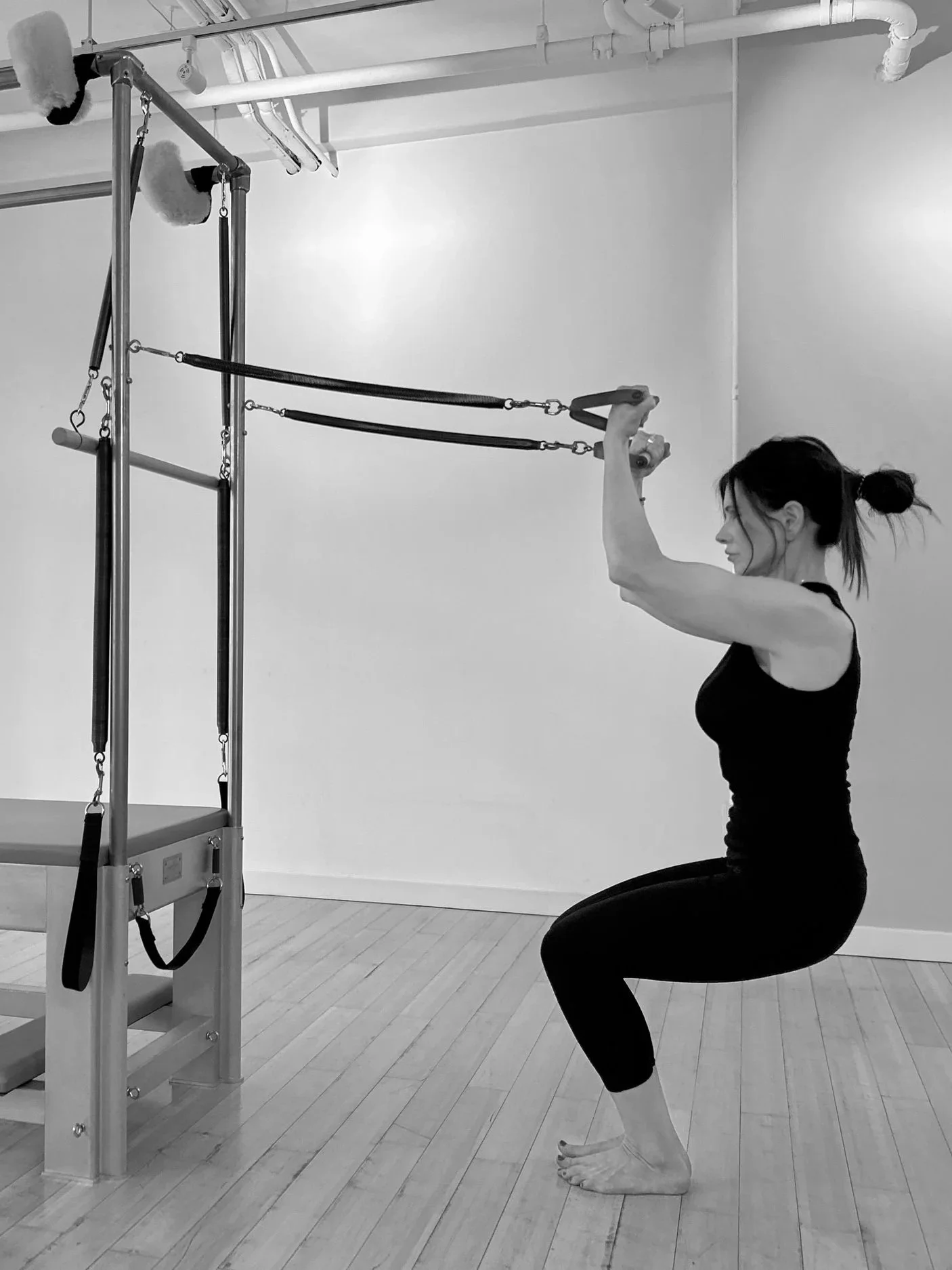 Client performing squat exercise on Pilates Cadillac demonstrating strength and control in Davis CA studio