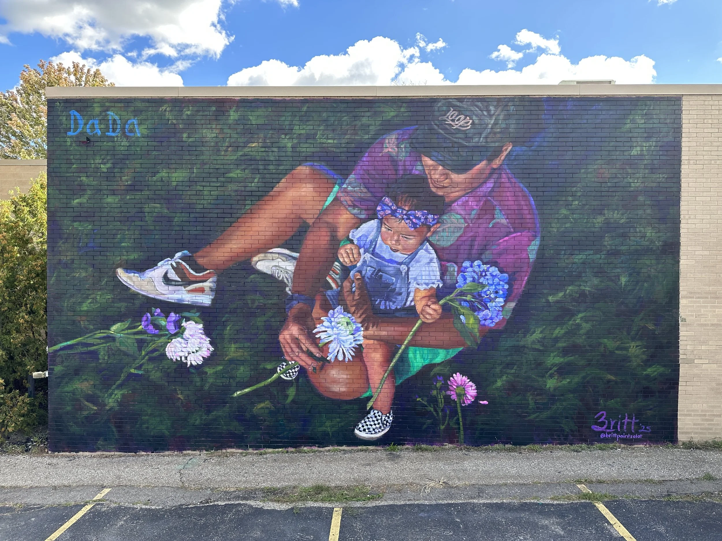 Colorful mural of a person playing with a young child outdoors, with flowers and greenery around them.