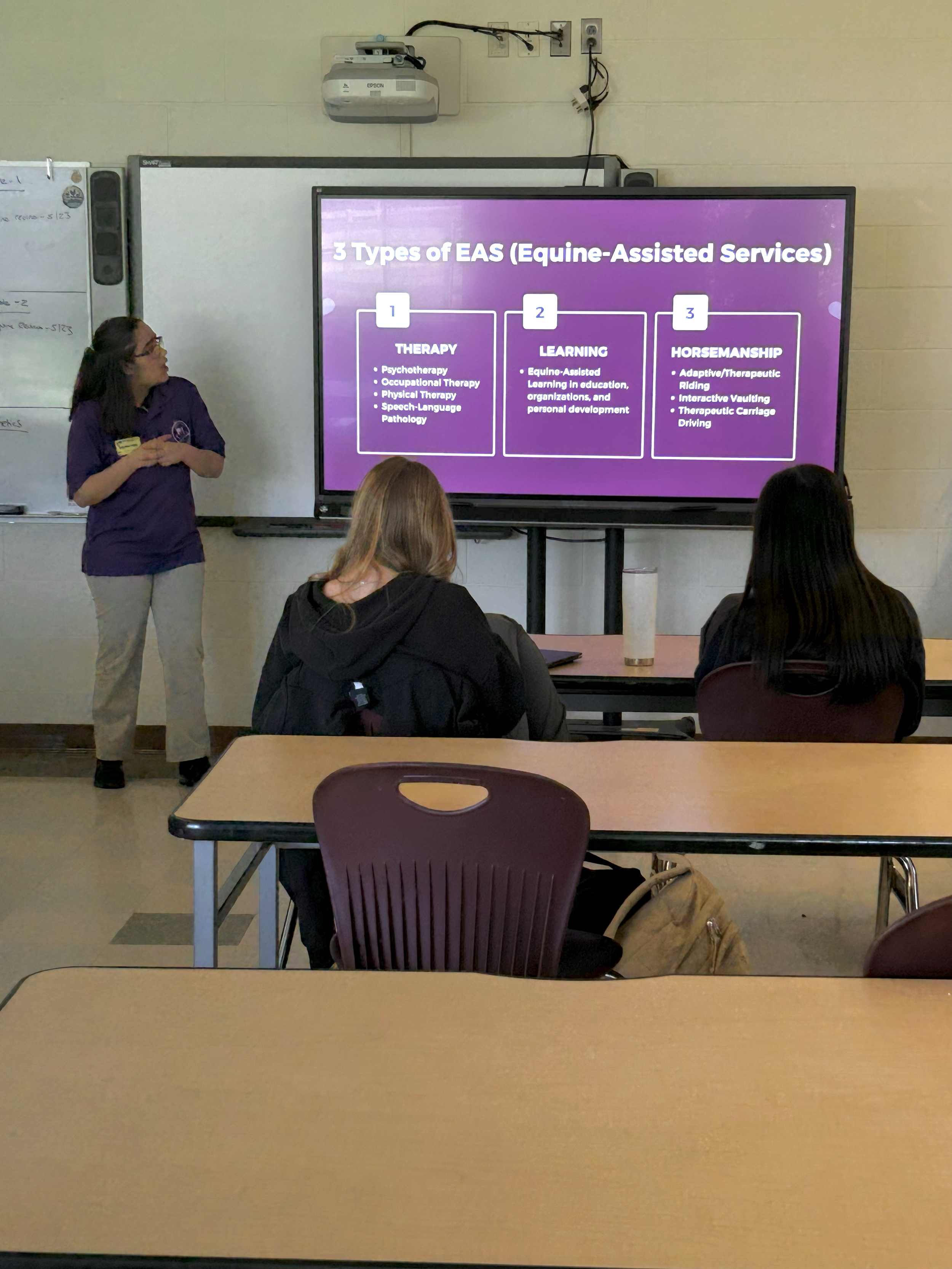 Classroom presentation on equine-assisted services with an instructor and students sitting at desks.